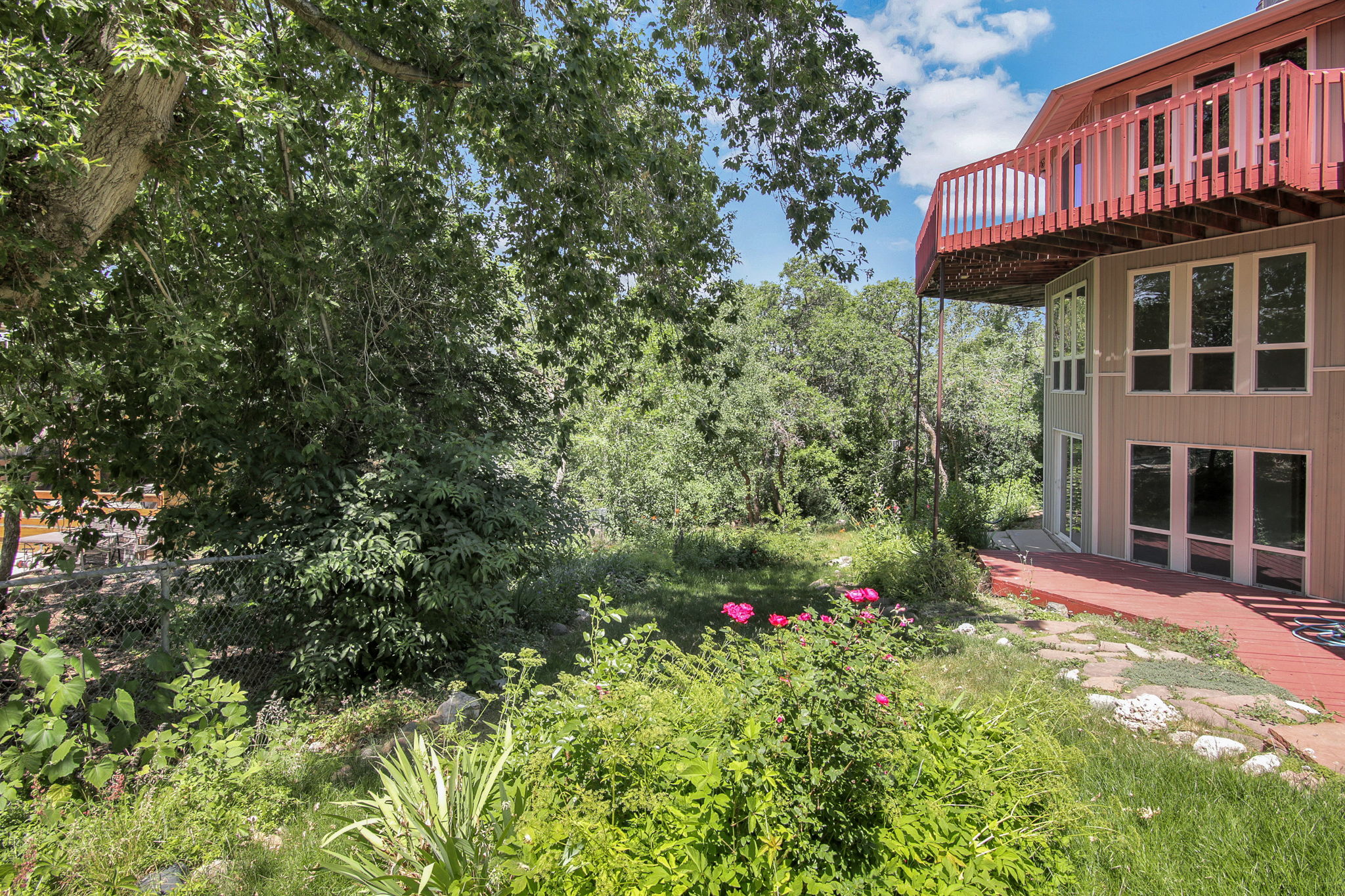 Terraced landscaping with mature trees and vibrant foliage. View of decking