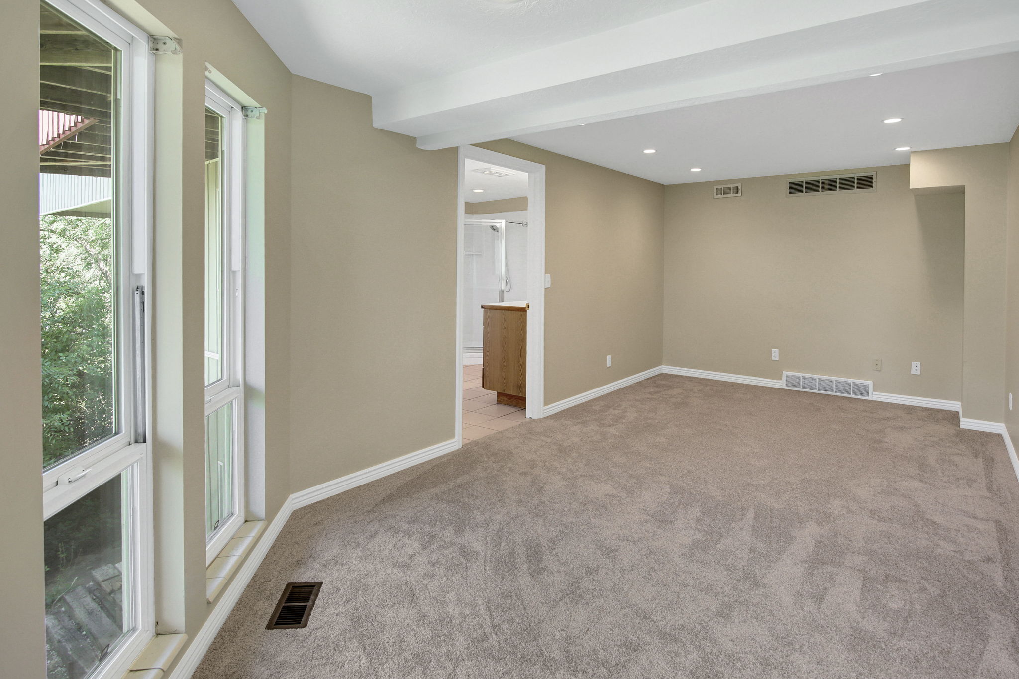 Second primary suite with view into full bathSpacious room featuring neutral carpeting and wall paint