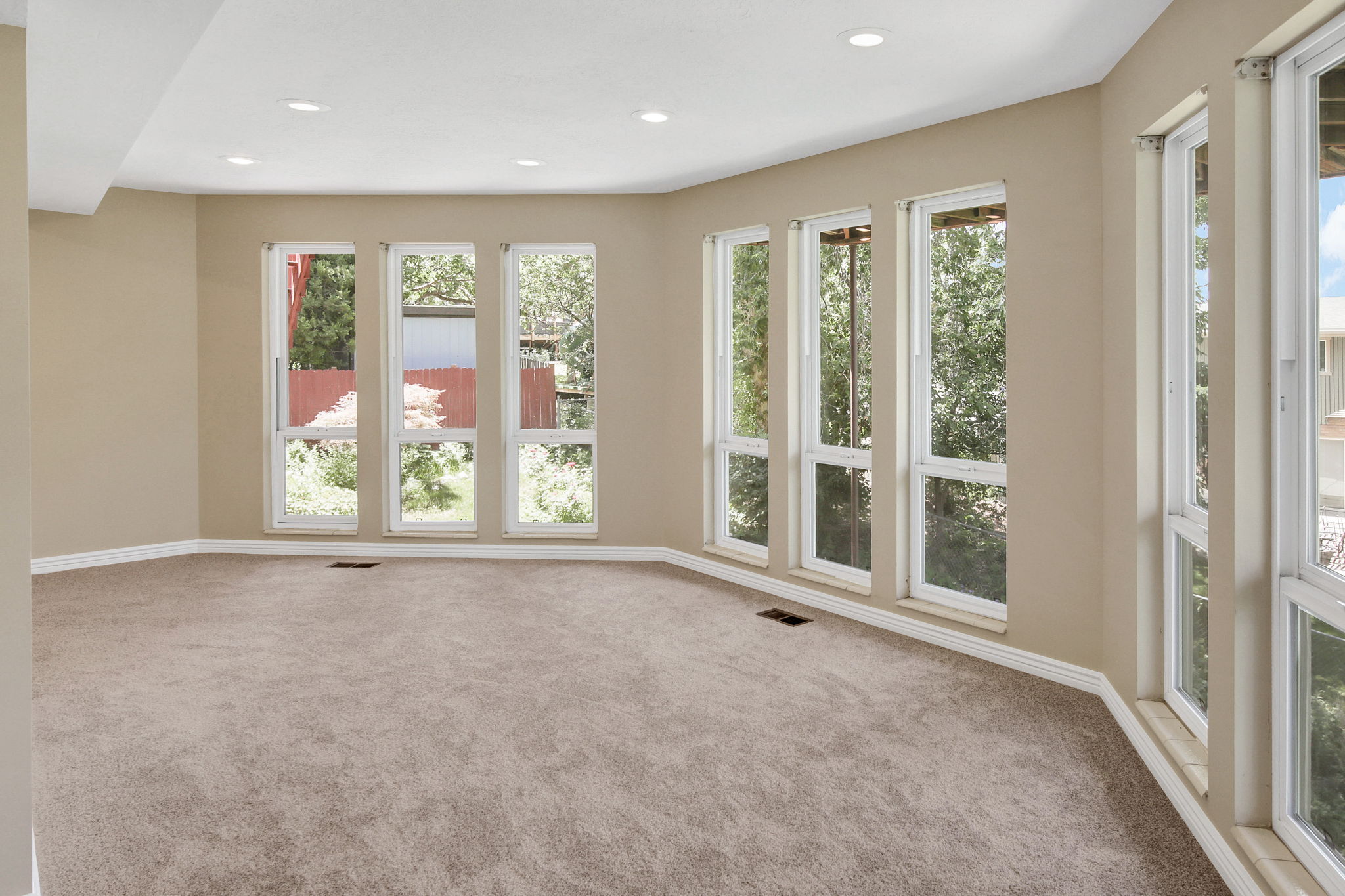 View 3 Spacious primary bedroom featuring extensive window placement, recessed ceiling lighting, light beige wall paint, white baseboards, views