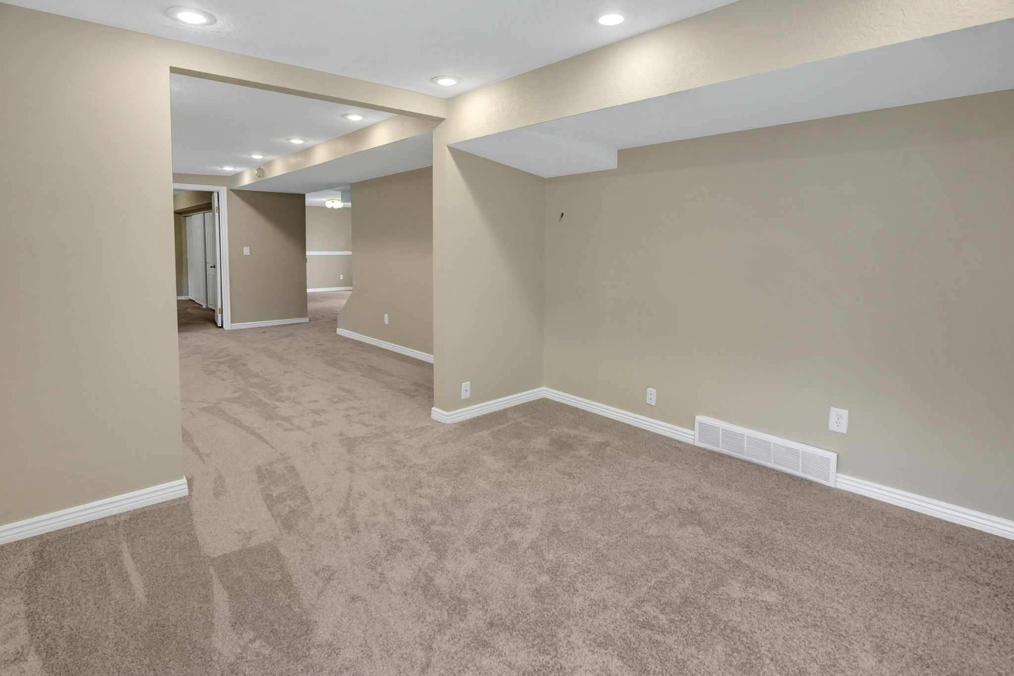 Spacious interior room with neutral-toned carpeting, recessed ceiling lighting, and light beige wall paint Reverse view to bedroom and den office