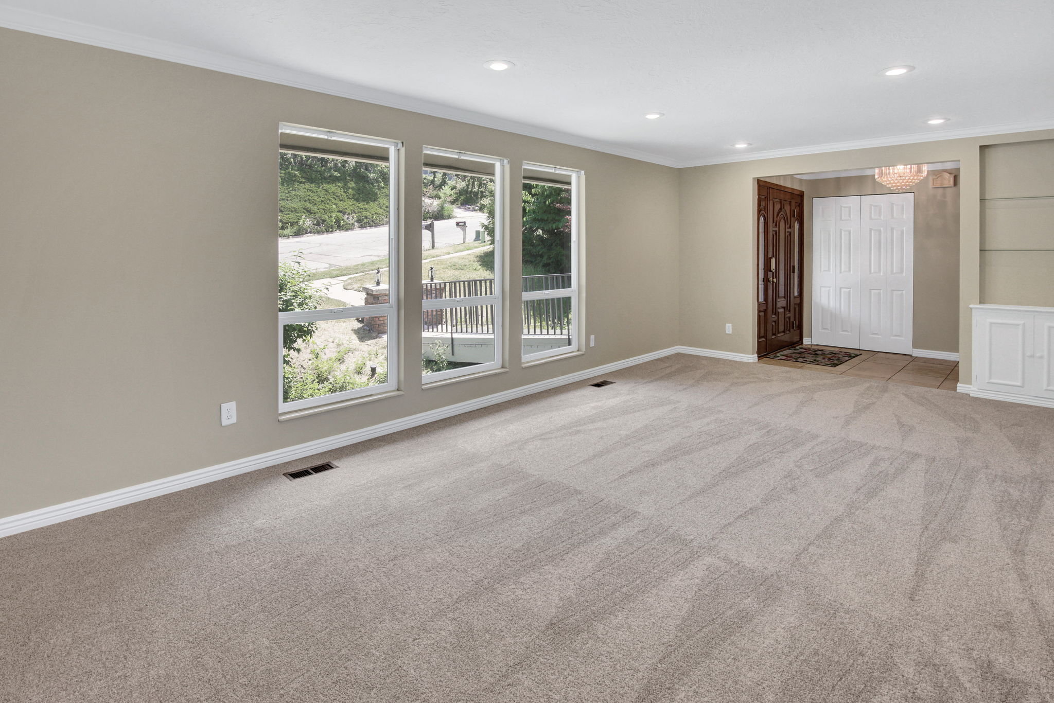 Spacious living area featuring New neutral carpeting and freshly painted light-toned walls, formal entry and built in shelf