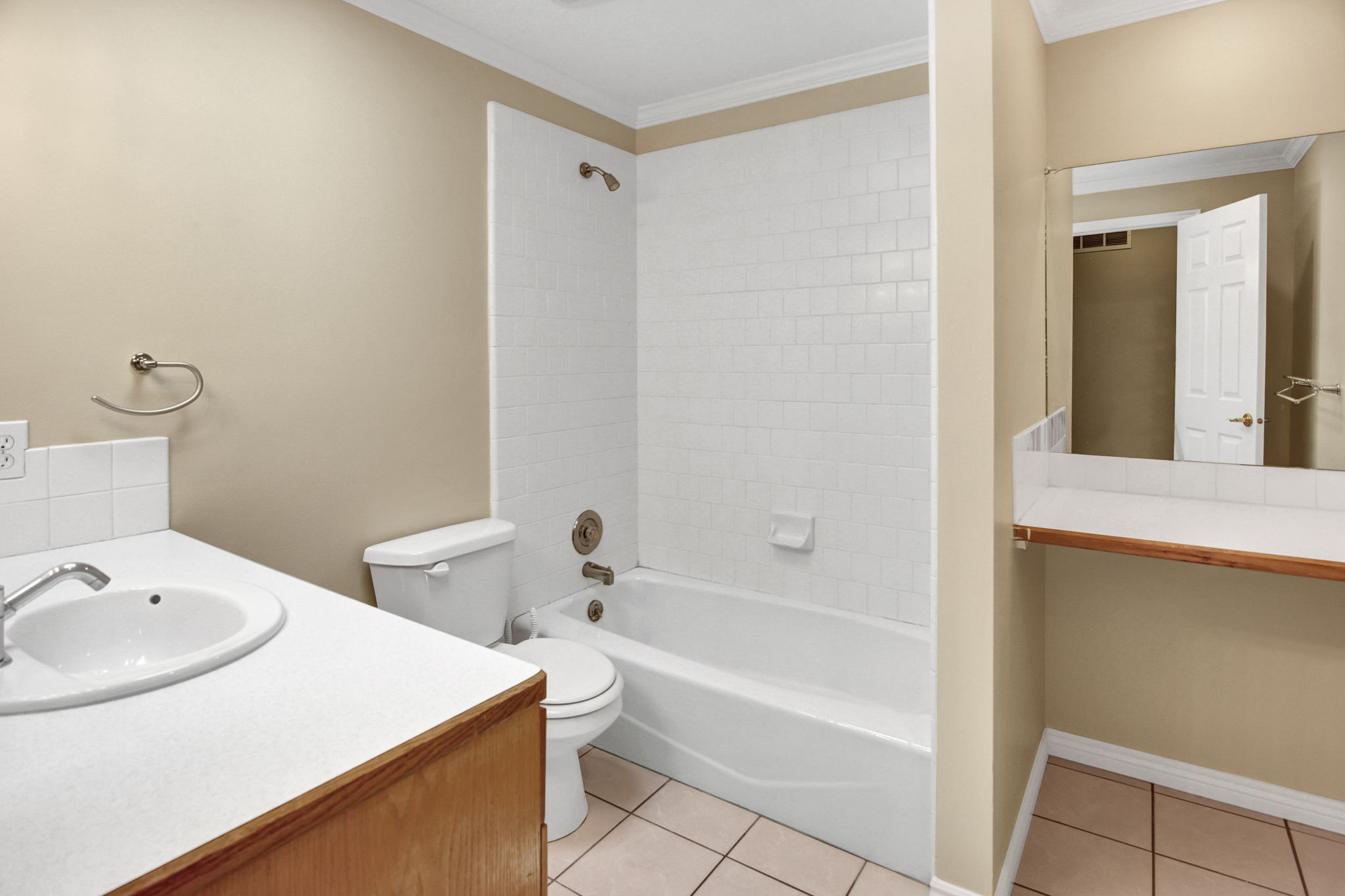 Main Bathroom featuring a white bathtub, ceramic tile shower surround, and a vanity with an integrated sink,  additional mirrored make up vanity