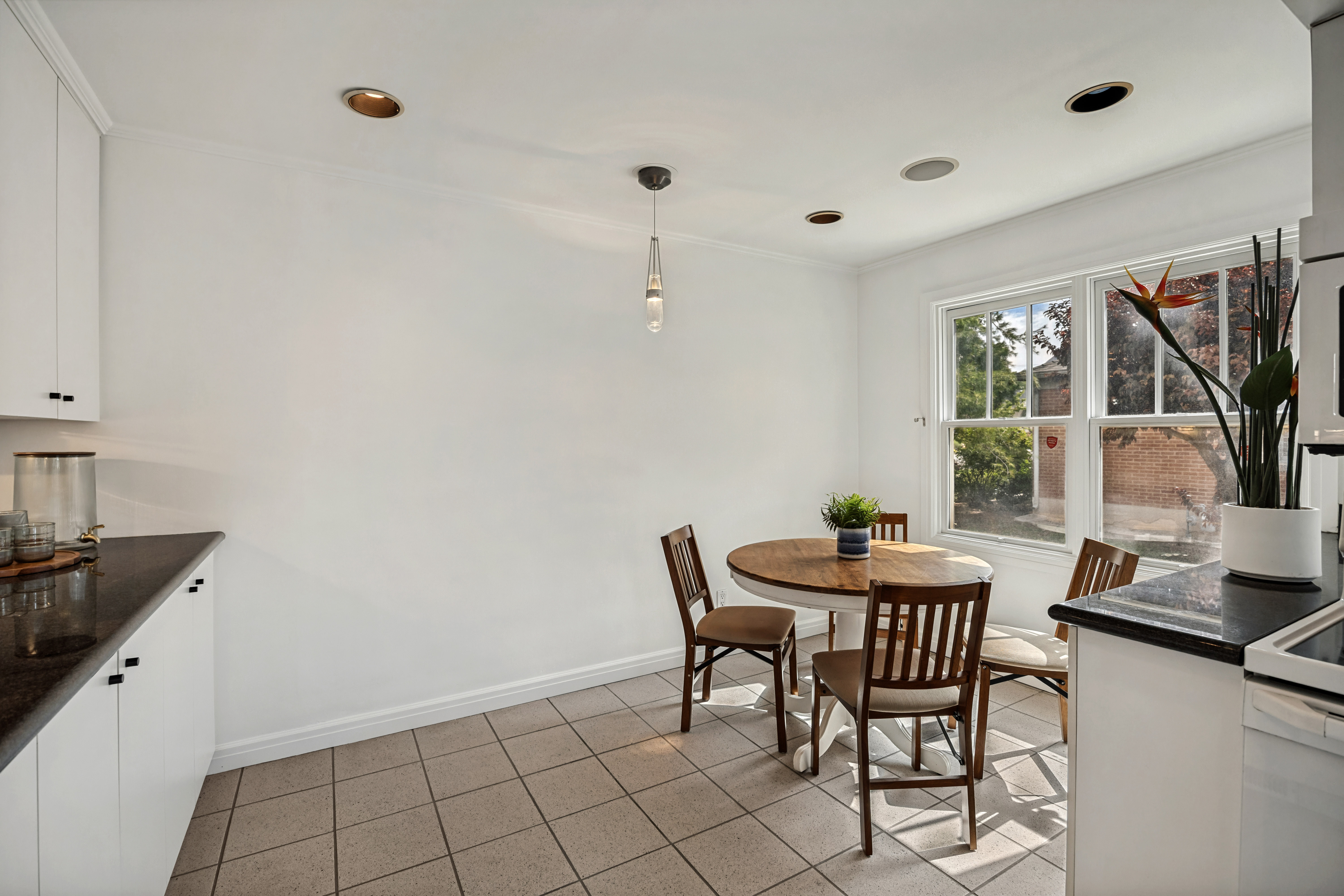 Recessed ceiling lighting complements a contemporary pendant fixture over a tiled floor