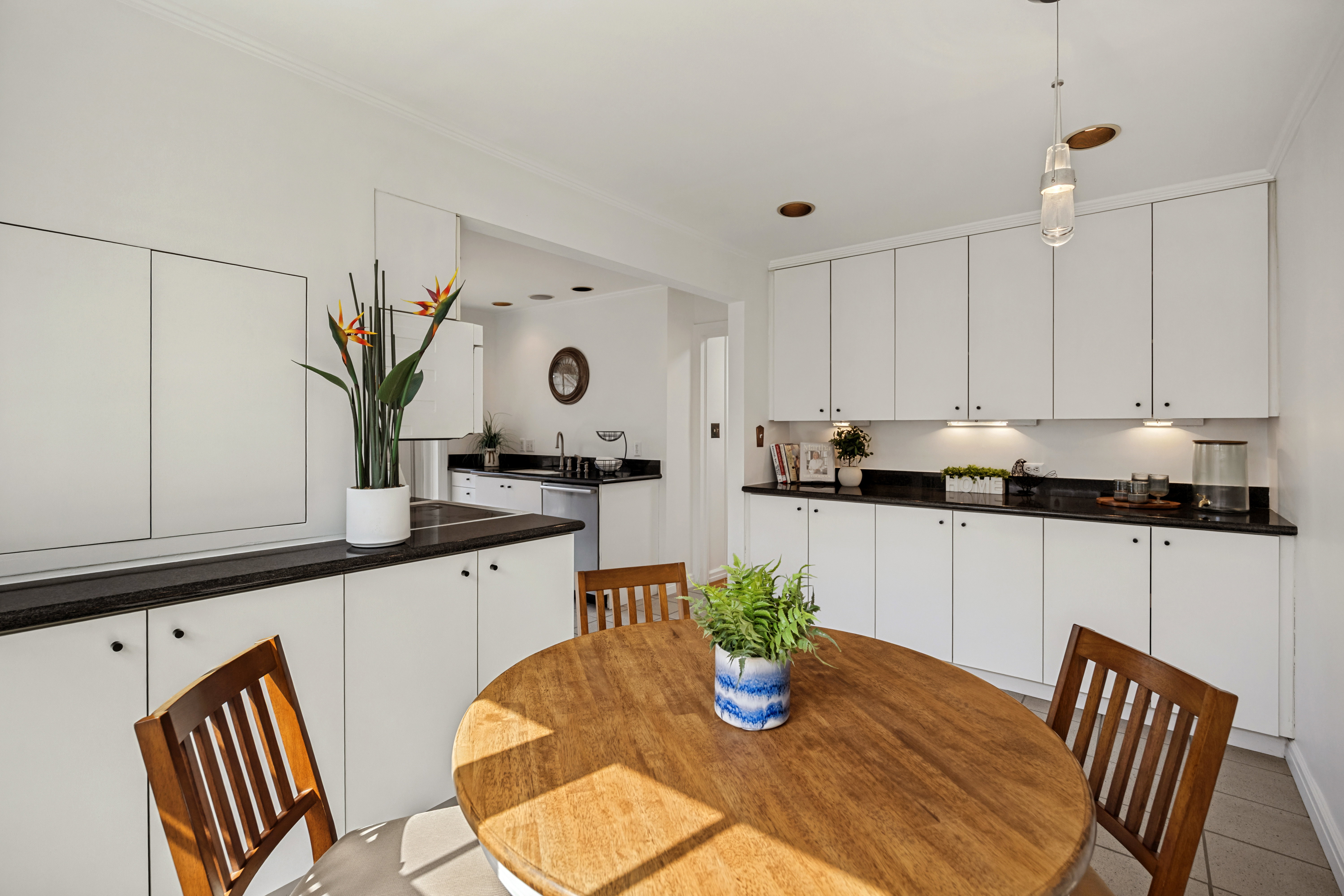 Kitchen and dining area featuring white cabinetry, dark countertops, a pendant light fixture, and tile flooring