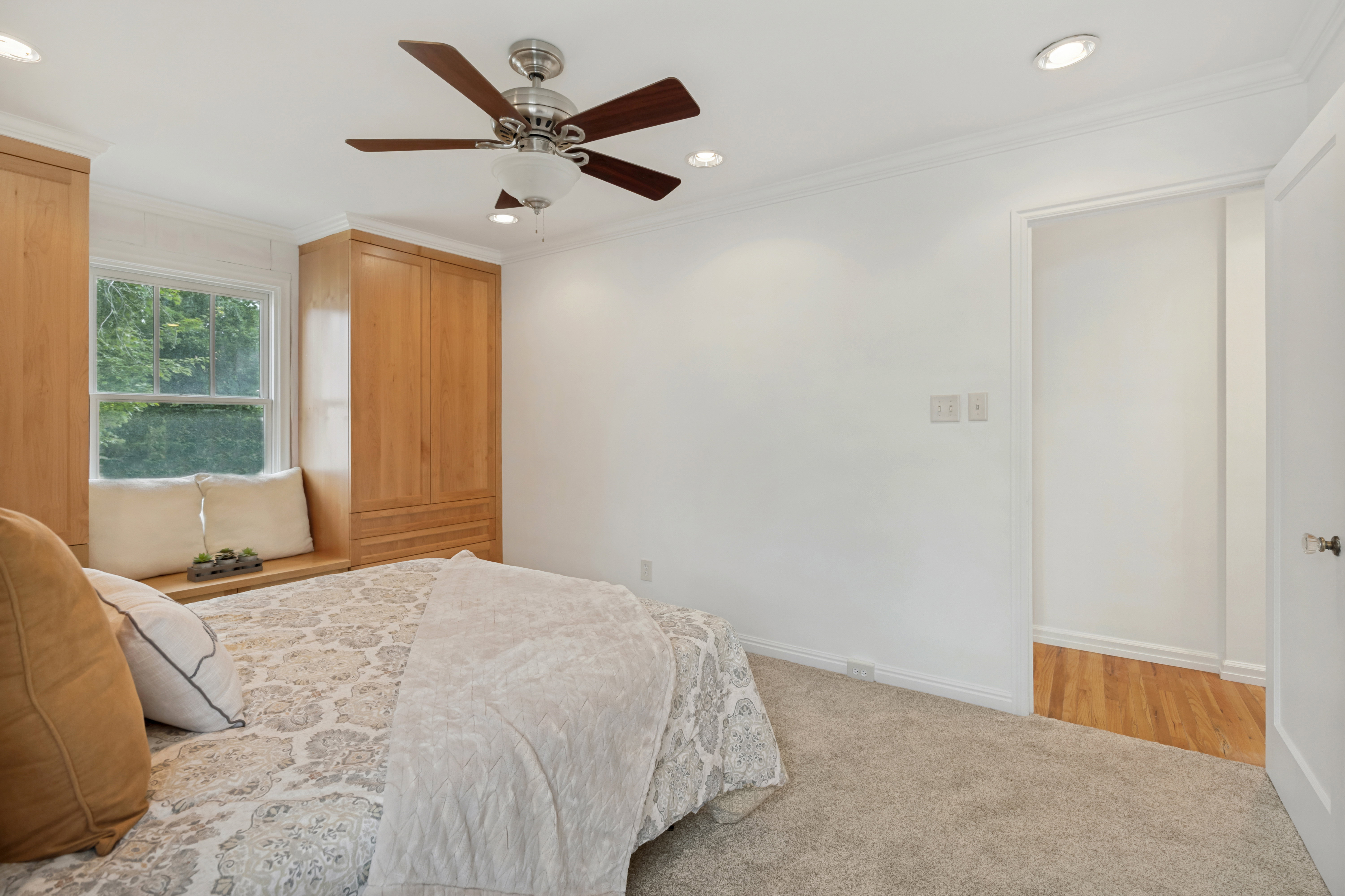 Bedroom featuring light-toned built-in cabinetry, a window seat, and a ceiling fan with light