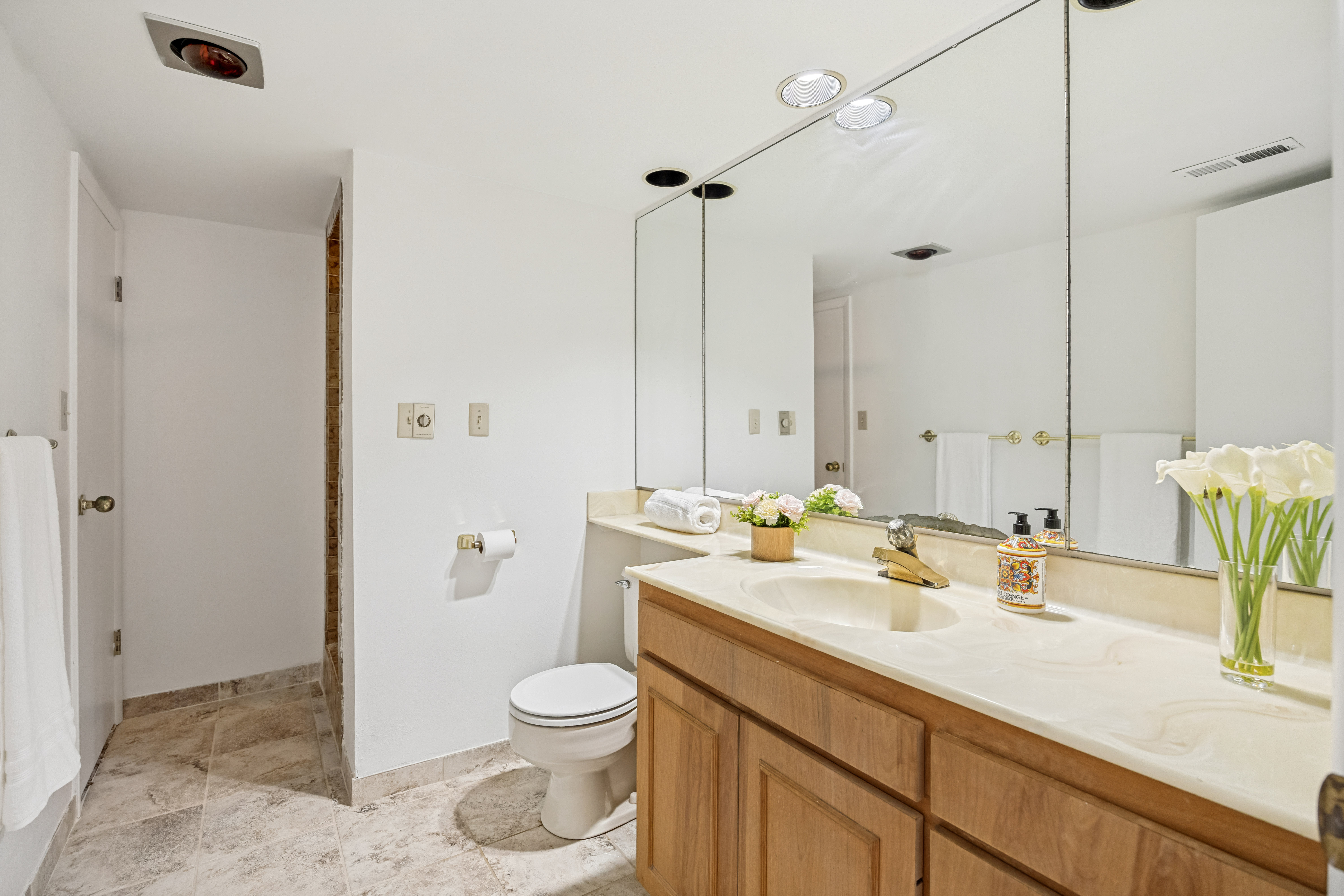 Bathroom featuring a light-toned vanity with an integrated sink, a large wall-mounted mirror, recessed lighting, and tiled flooring