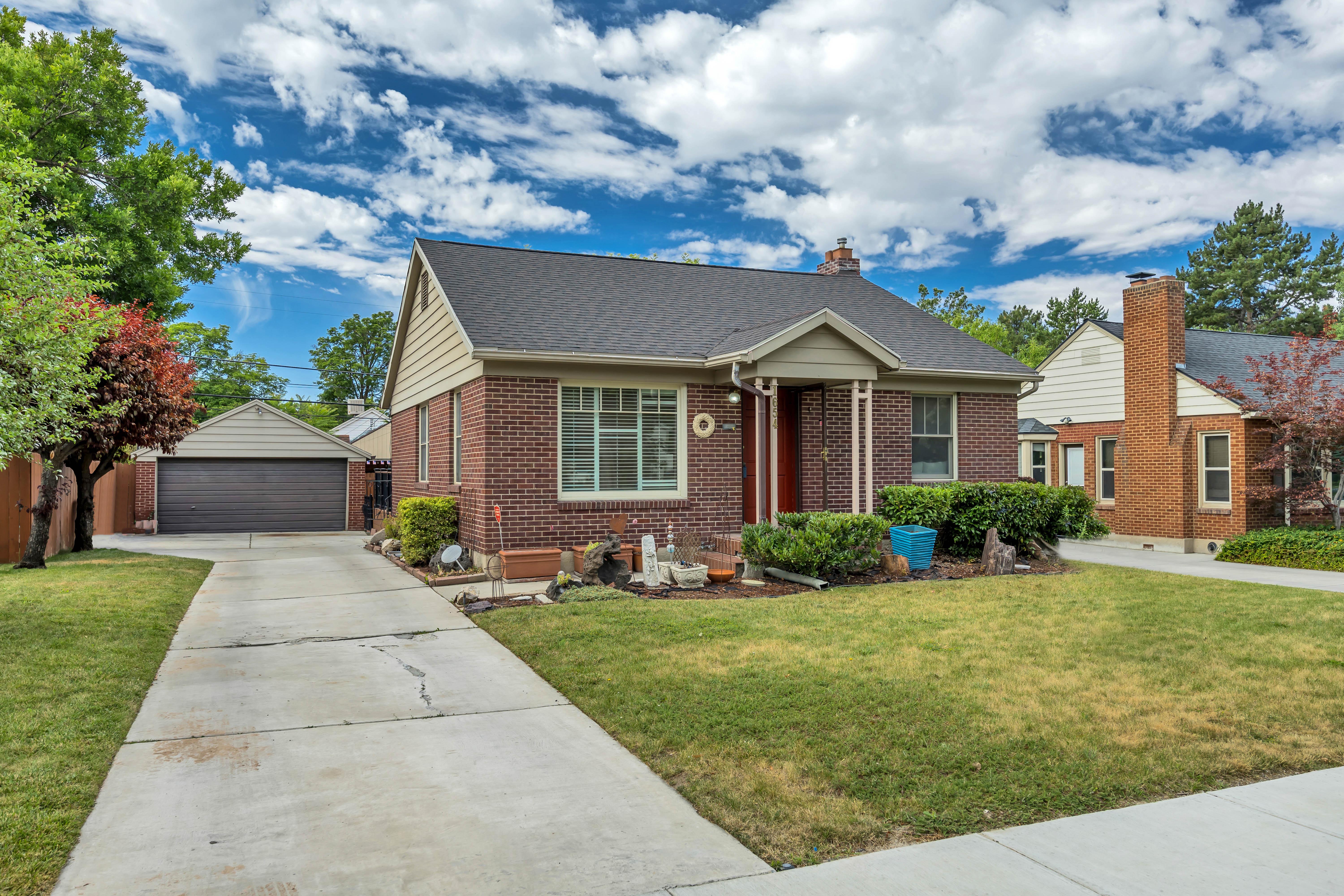Traditional brick residence featuring a dark shingle roof, a covered entry, and a prominent front lawn