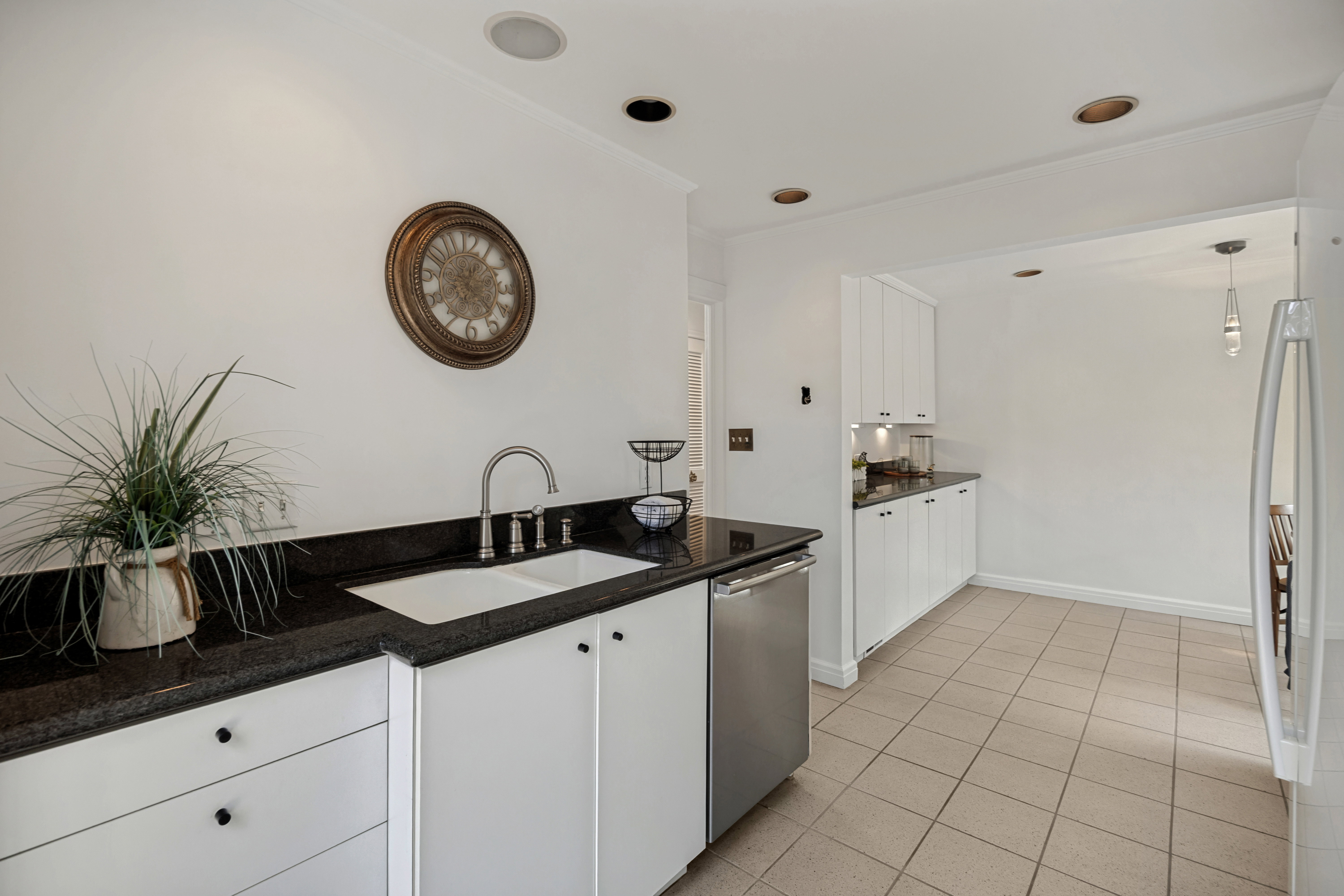 Kitchen featuring white cabinetry, dark stone countertops, a dual-basin sink with a gooseneck faucet, a stainless steel dishwasher, and recessed lighting