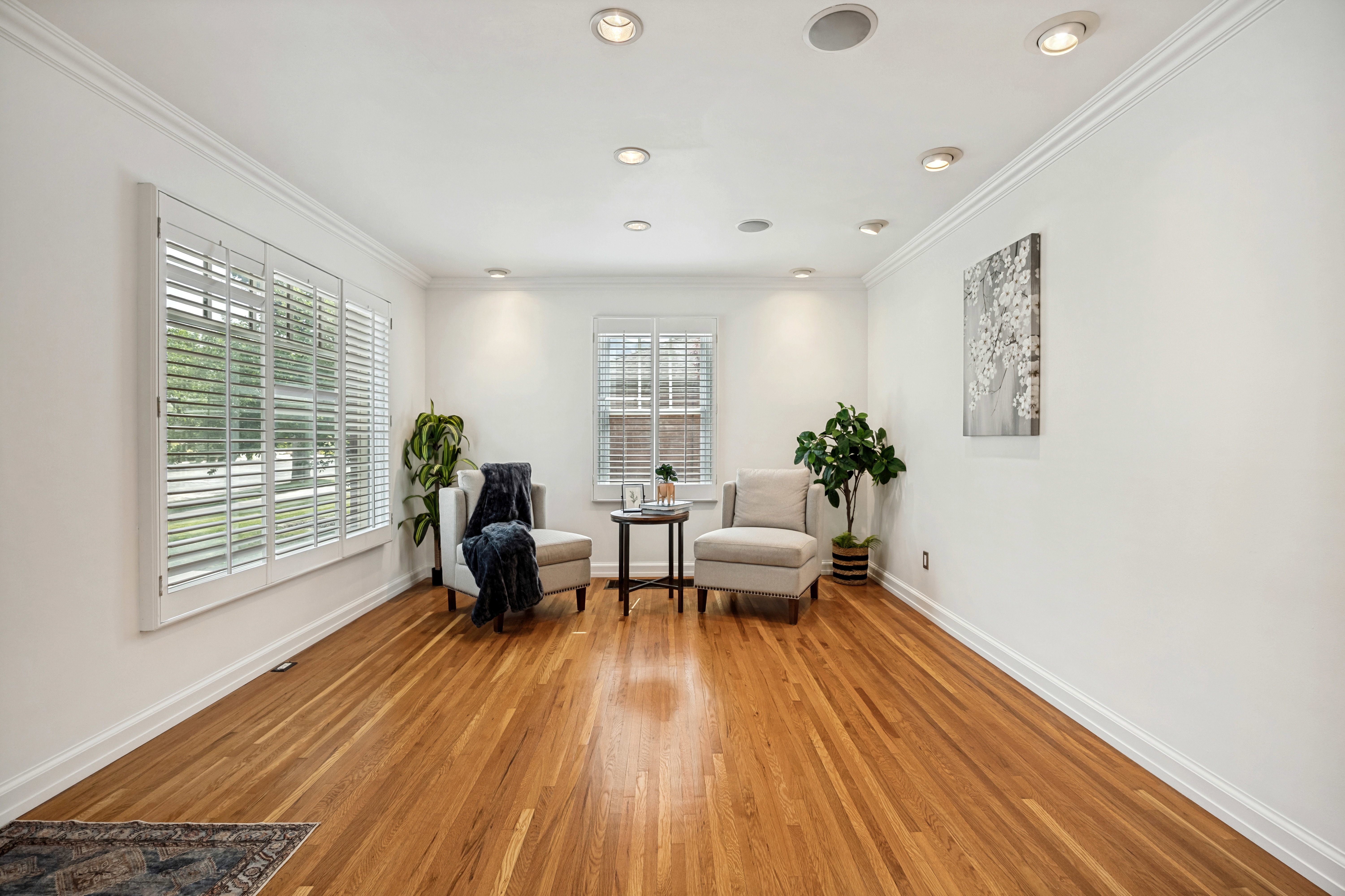 Hardwood flooring extends throughout this room, featuring recessed lighting and crown molding