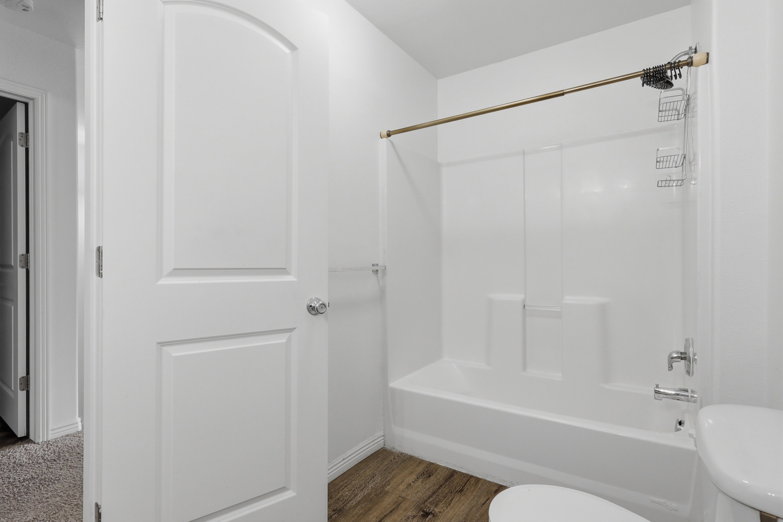 Full white bathroom featuring a tub/shower combination with chrome fixtures and a coordinating curtain rod