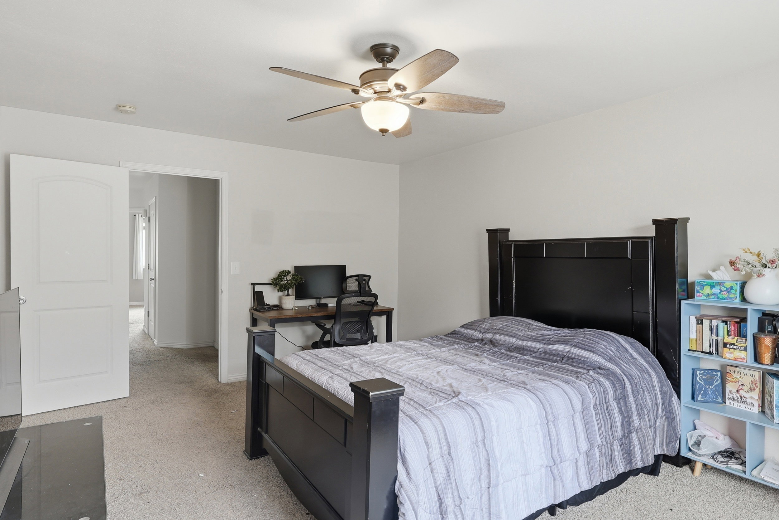 Carpeted interior room featuring light gray wall paint, a ceiling fan with light fixture, and white trim work