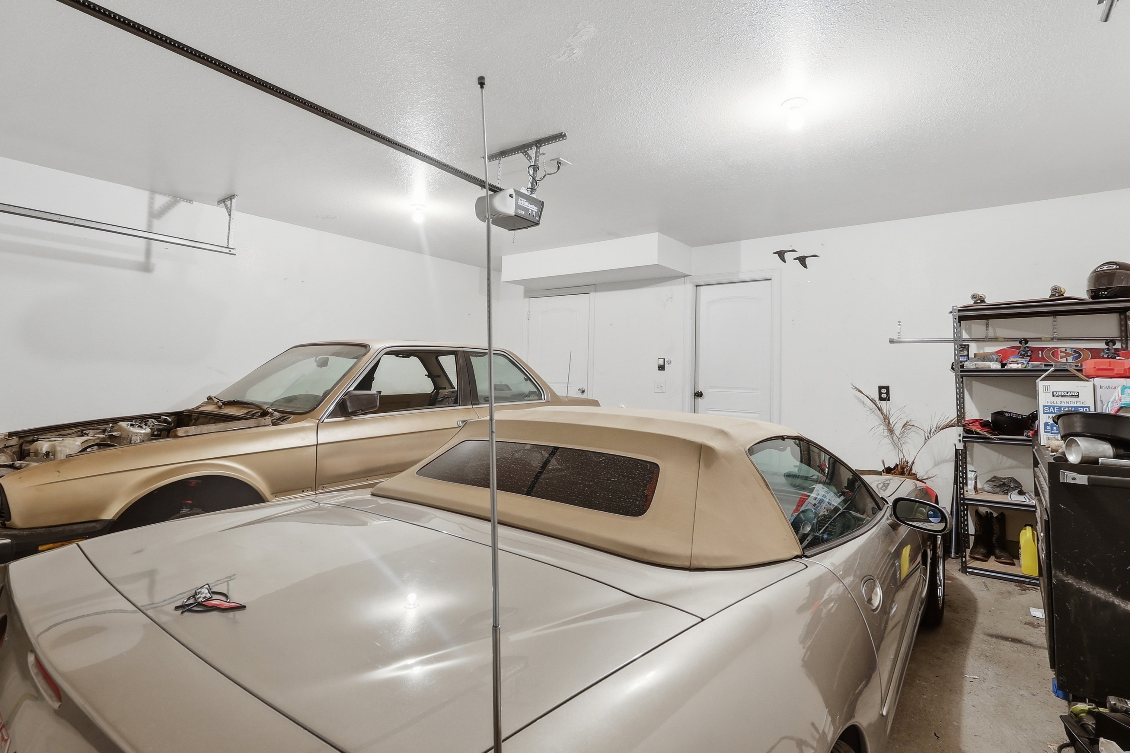 Spacious garage with overhead lighting, white walls, and a visible garage door opener mechanism