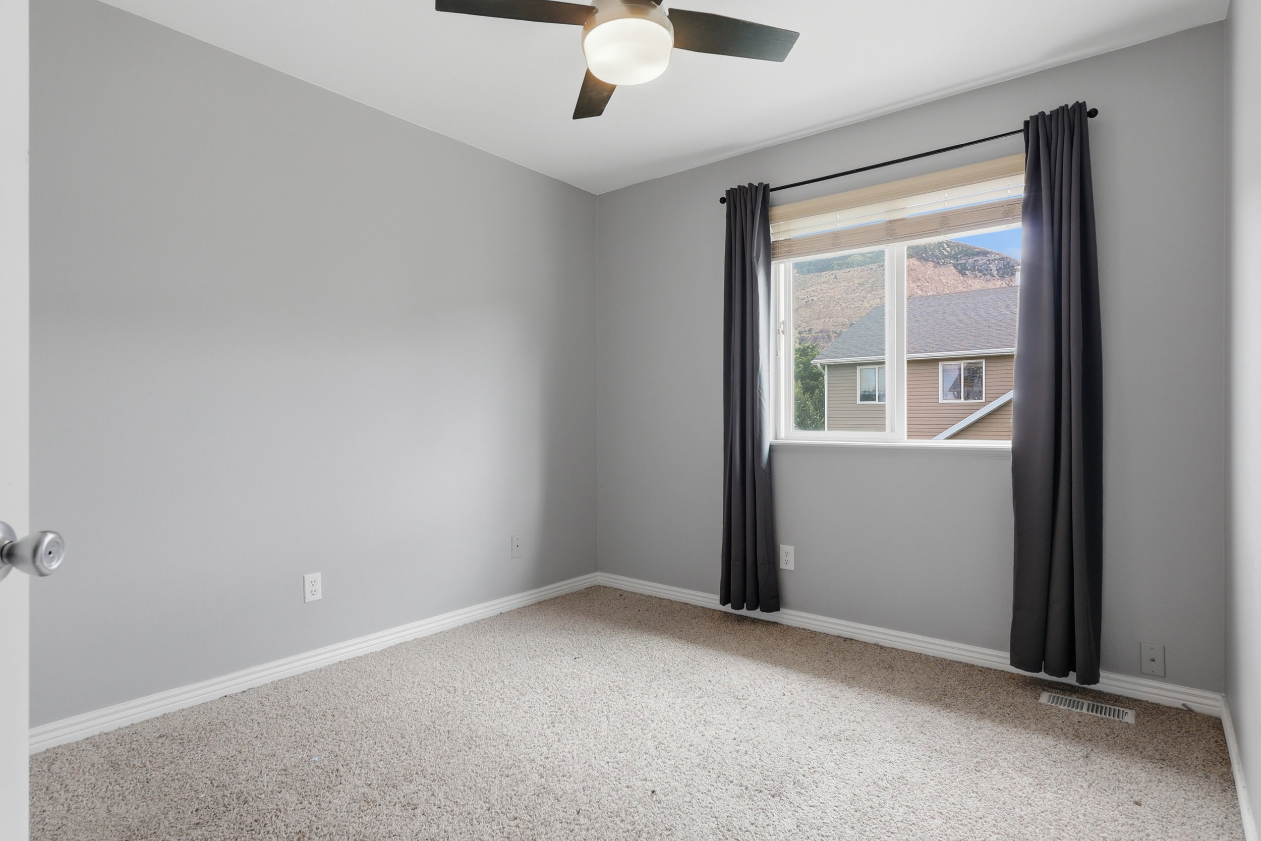 Room featuring a window with mountain scenery, a ceiling fan with integrated lighting, light-toned carpeting, and a neutral wall color