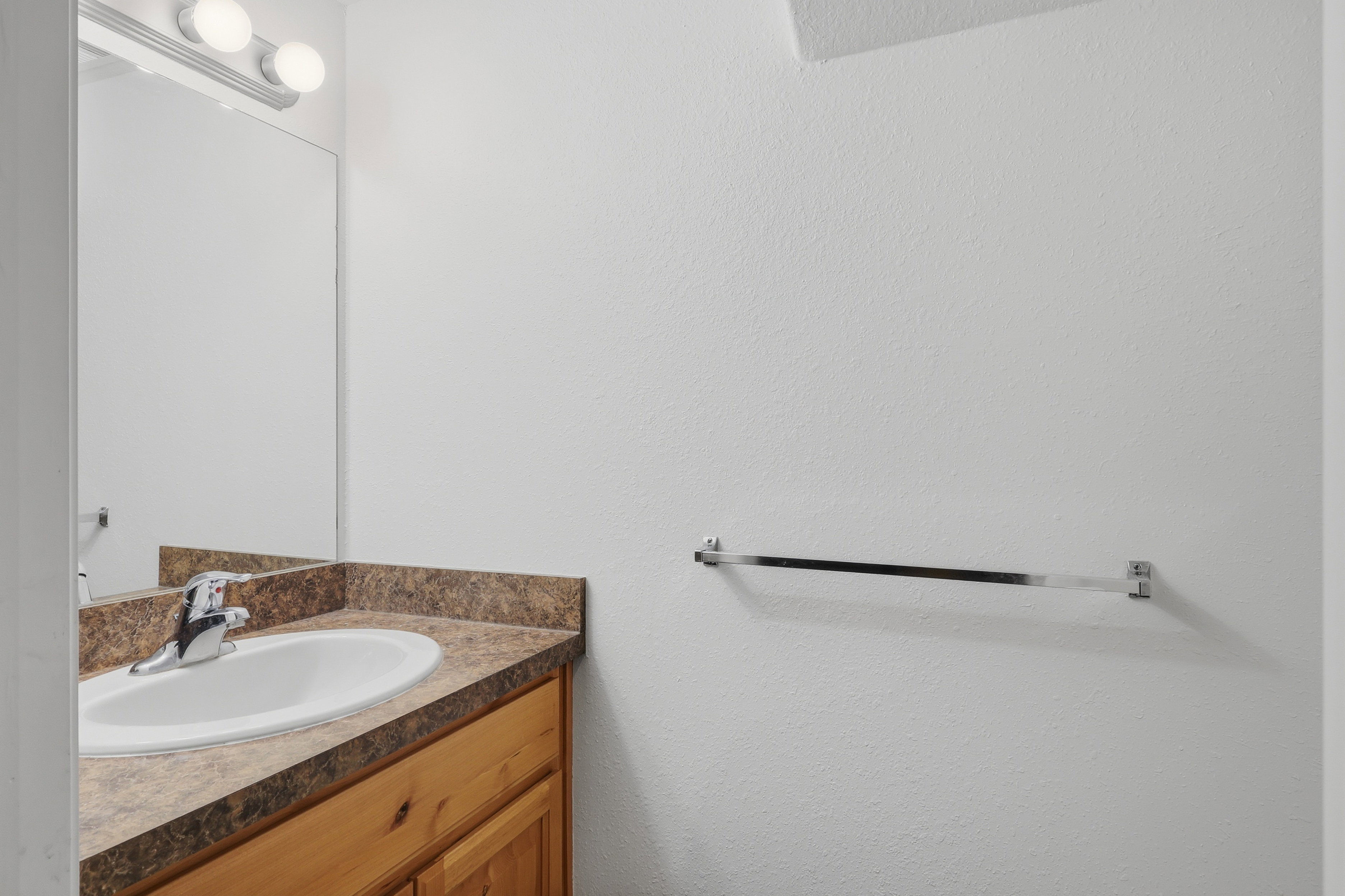 Bathroom vanity featuring a laminate countertop, integrated sink, and wood-finish cabinetry