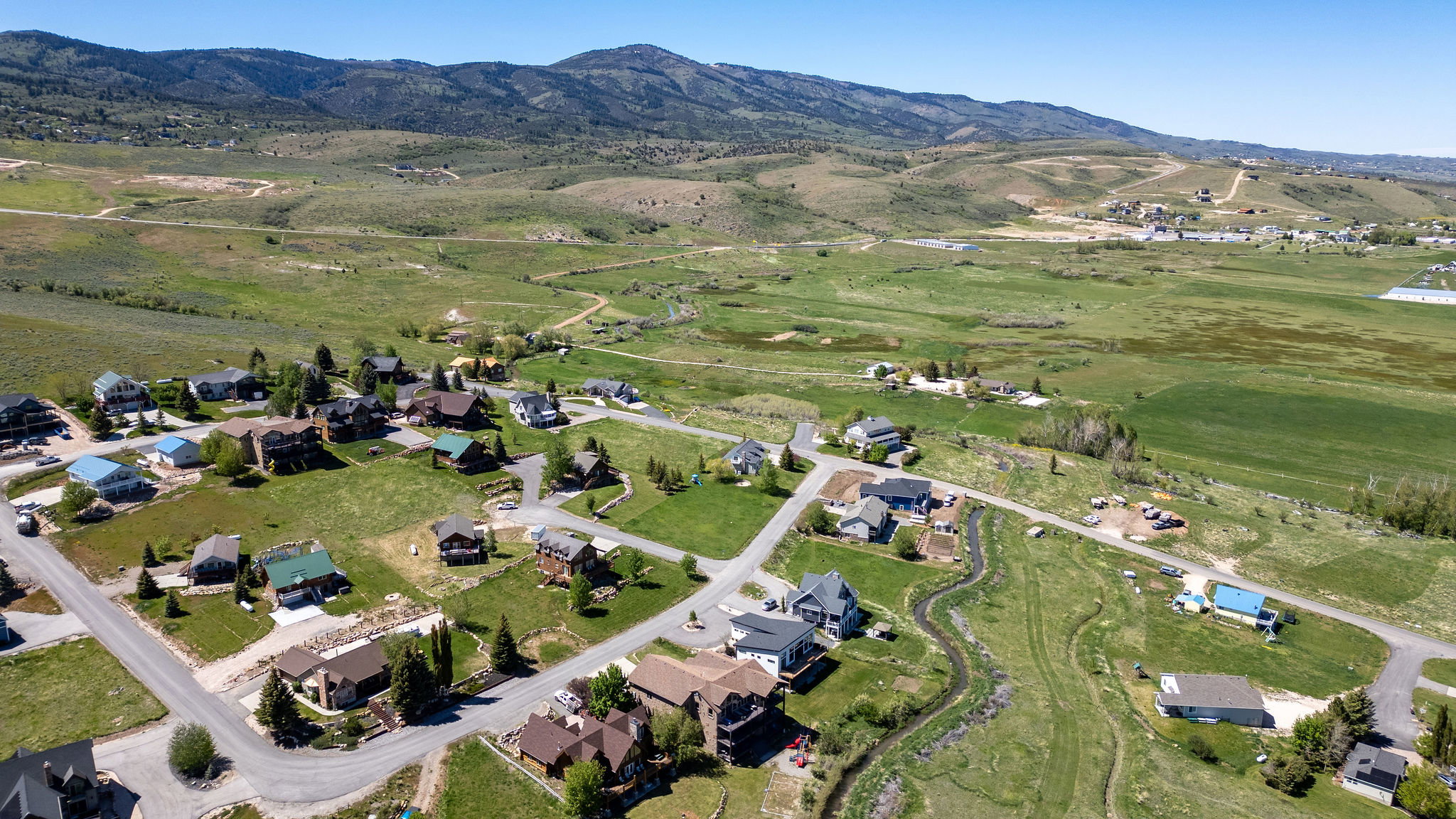 Expansive landscape featuring scattered residential properties, paved roadways, and a natural water feature