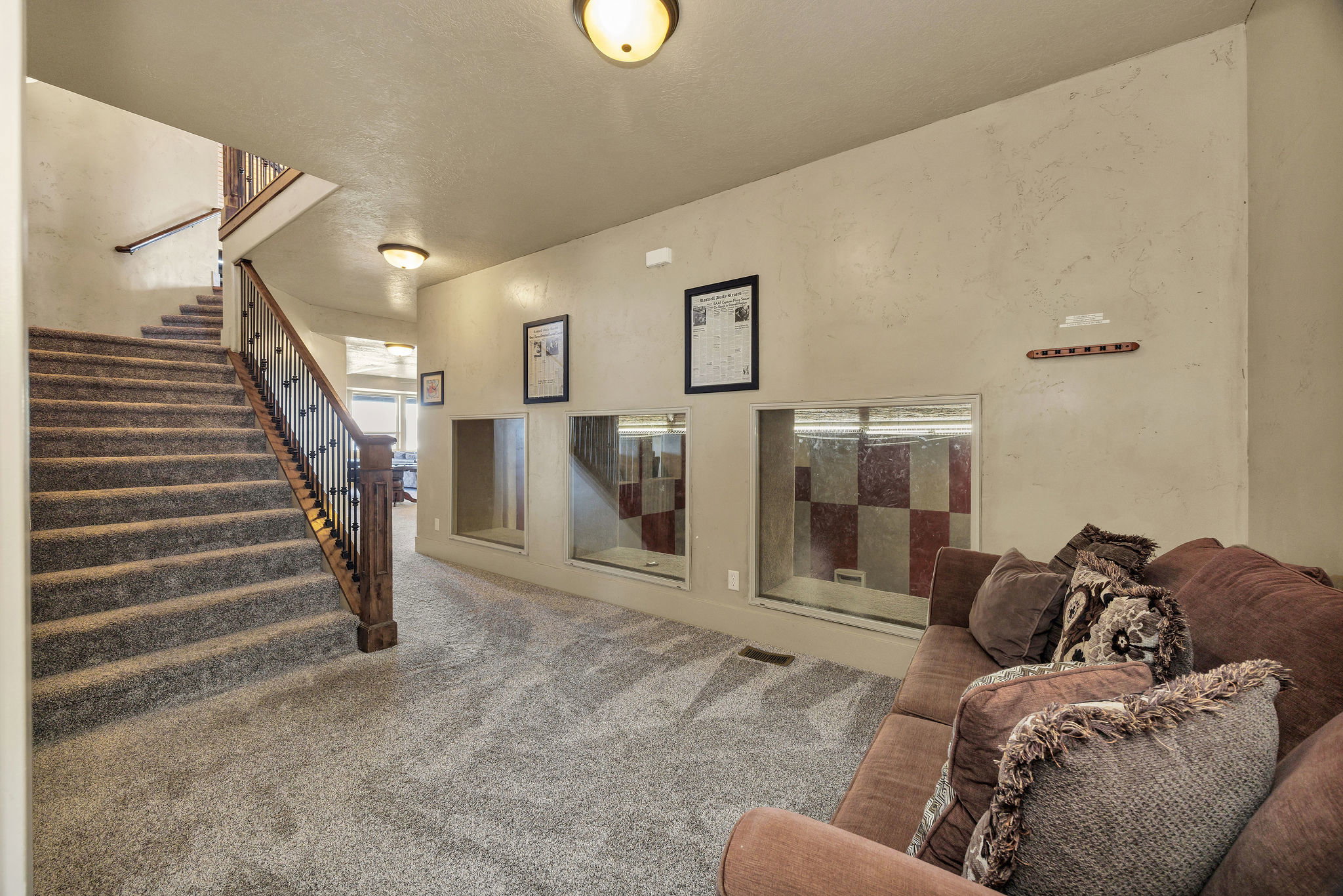 Carpeted staircase with dark wood newel post and wrought iron balusters