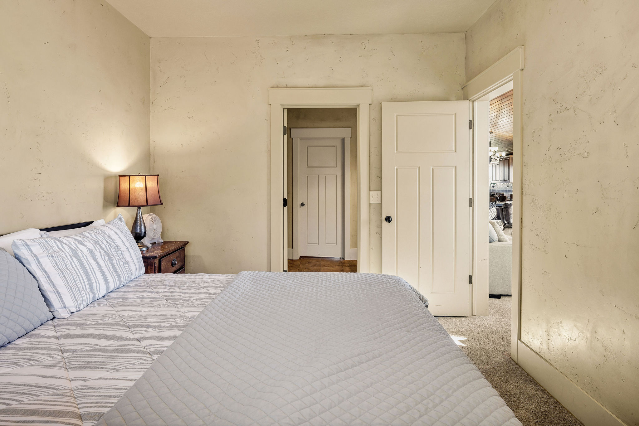 Bedroom featuring textured walls, carpet flooring, and a solid-core interior door with panel detailing