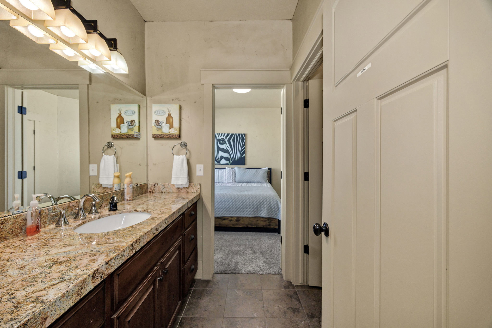 Bathroom vanity featuring a polished stone countertop, undermount sink, and dark wood cabinetry