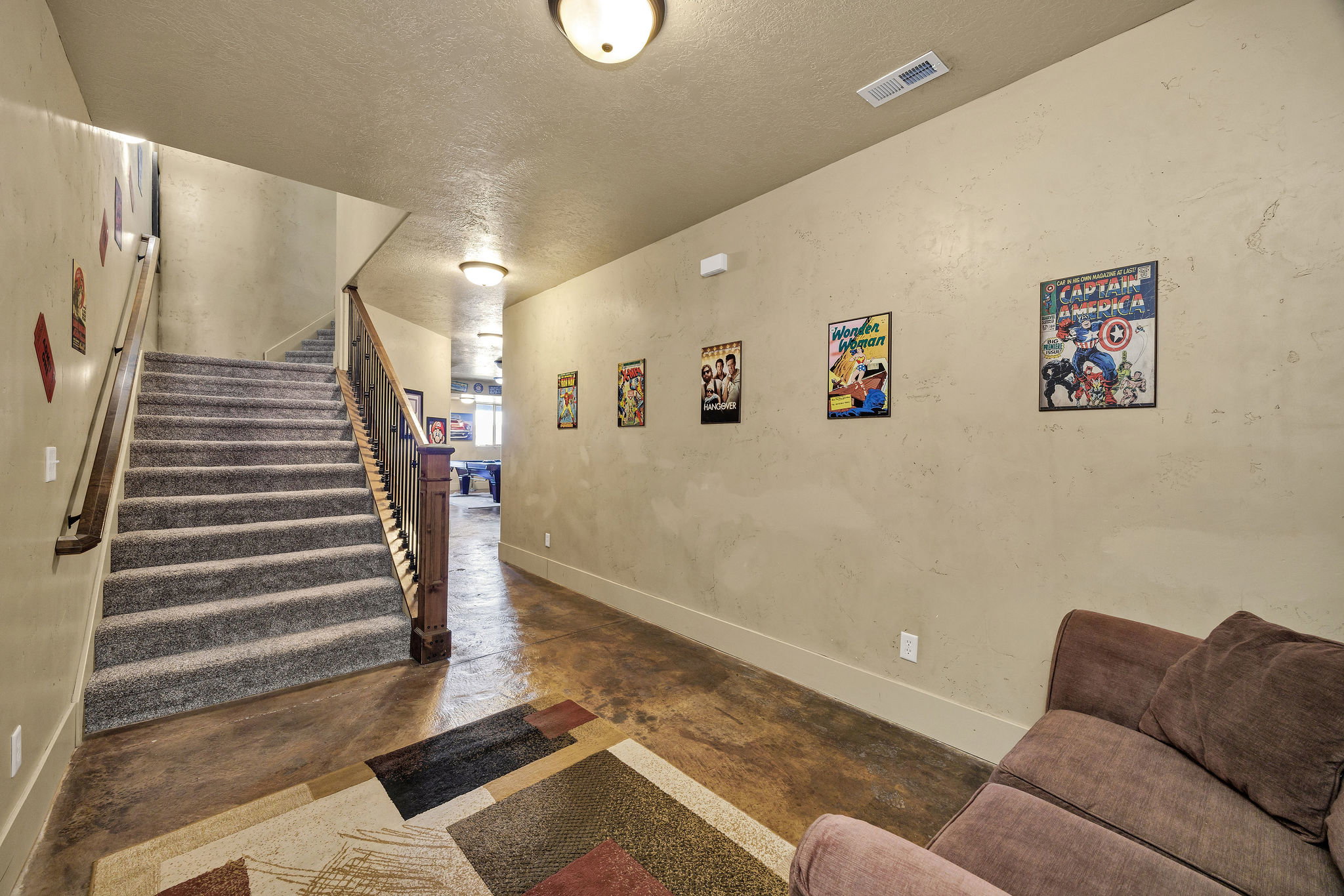 Staircase featuring carpeted treads and wood handrails with metal spindles, stained concrete flooring, and recessed ceiling lighting
