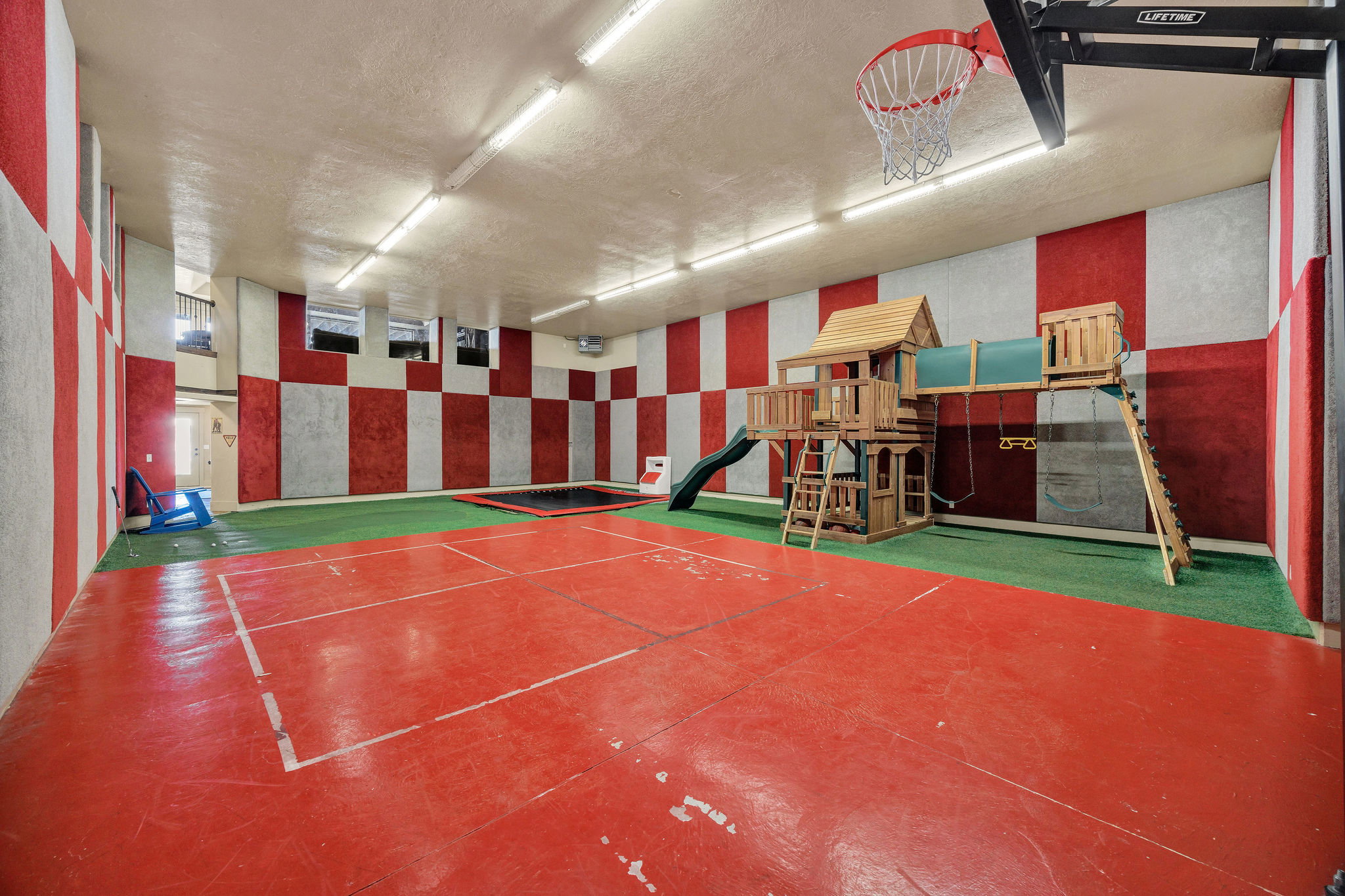 Indoor recreation space featuring a red-and-white checkered wall design and fluorescent ceiling lighting