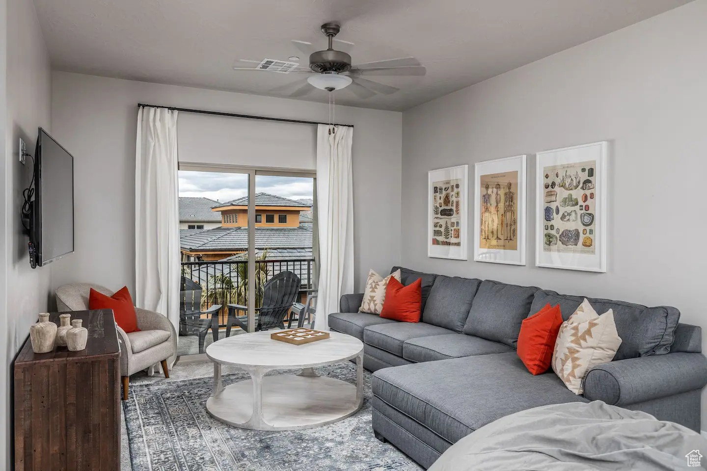 Living area featuring light gray walls, a ceiling fan with integrated lighting, and direct access to a private balcony through a glass sliding door