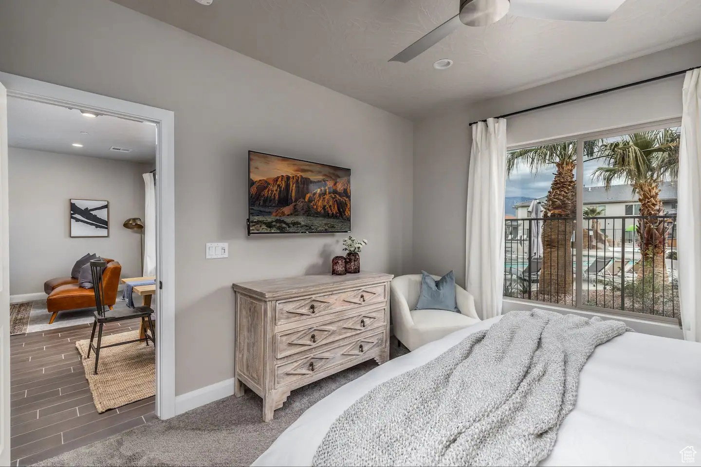 Bedroom featuring a contemporary ceiling fan, recessed lighting, and a large window overlooking a pool and palm trees