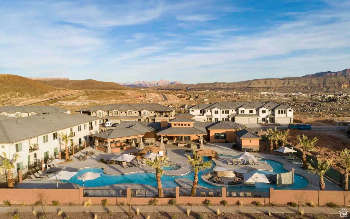 Expansive pool area featuring a winding river, multiple lounge areas with umbrellas, and palm tree accents
