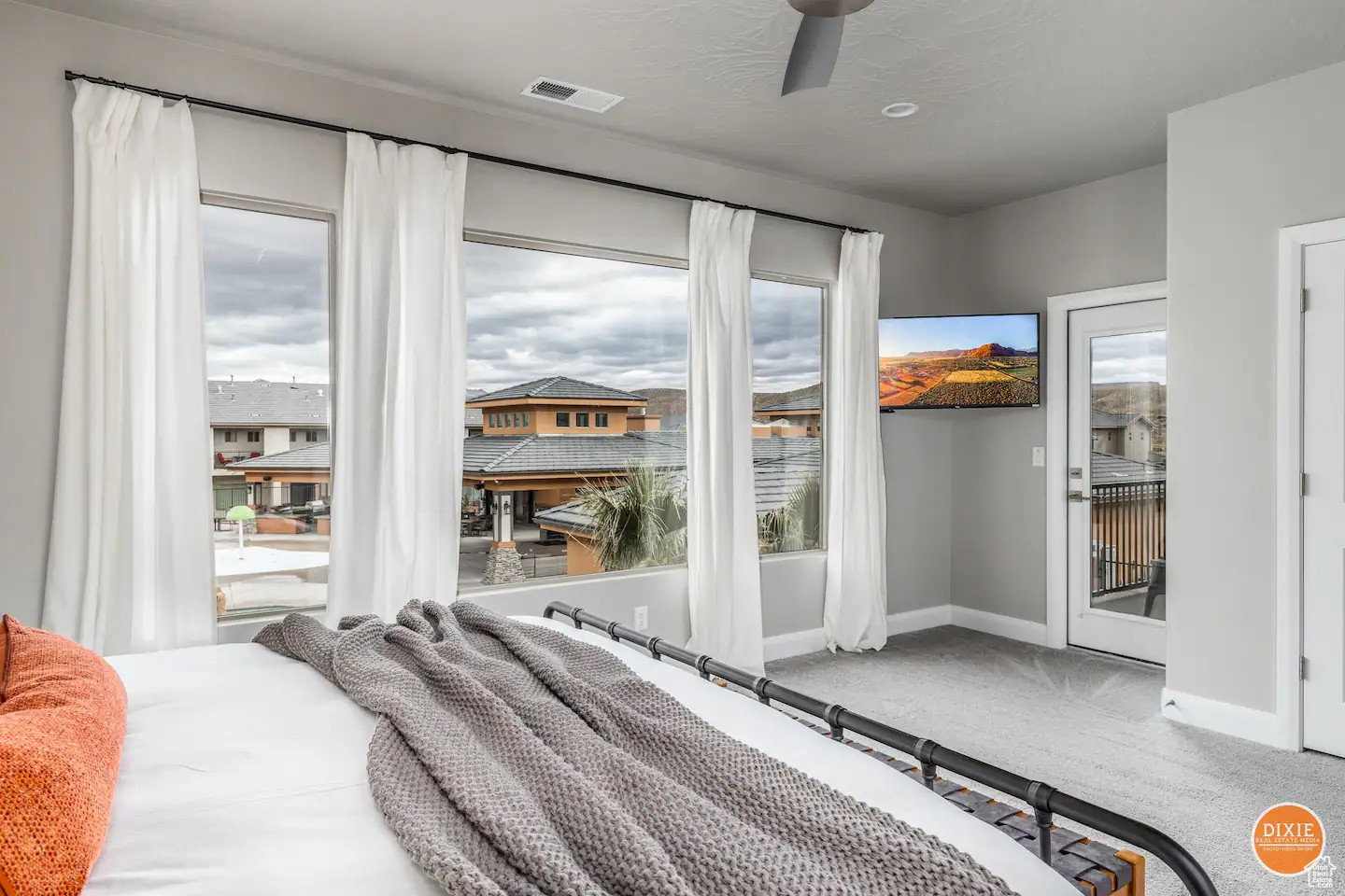 Bright interior room featuring a wall of four windows, a glass-panel exterior door, and a ceiling fan