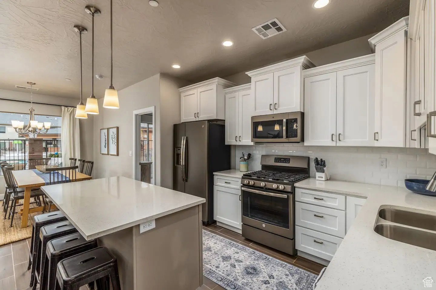 Open-concept kitchen with white shaker cabinetry, stainless steel appliances, and light-toned countertops