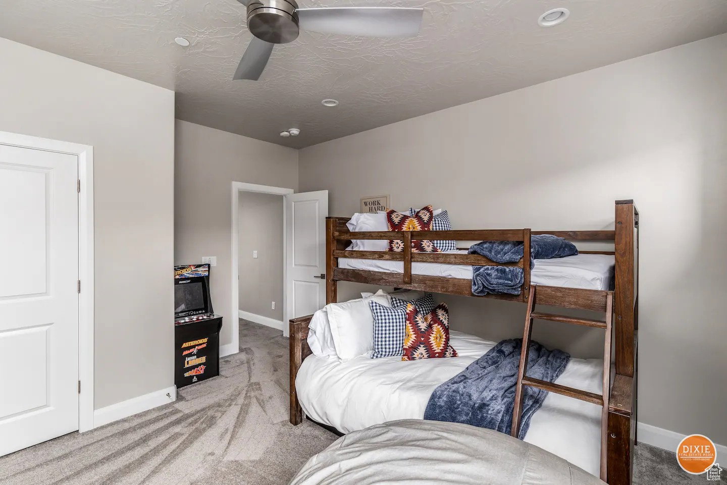 Room featuring light gray walls, gray patterned carpet flooring, and a ceiling fan with integrated lighting
