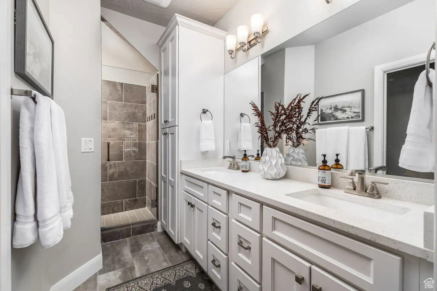 Bathroom featuring a dual vanity with white cabinetry, integrated sinks, and light-toned countertops