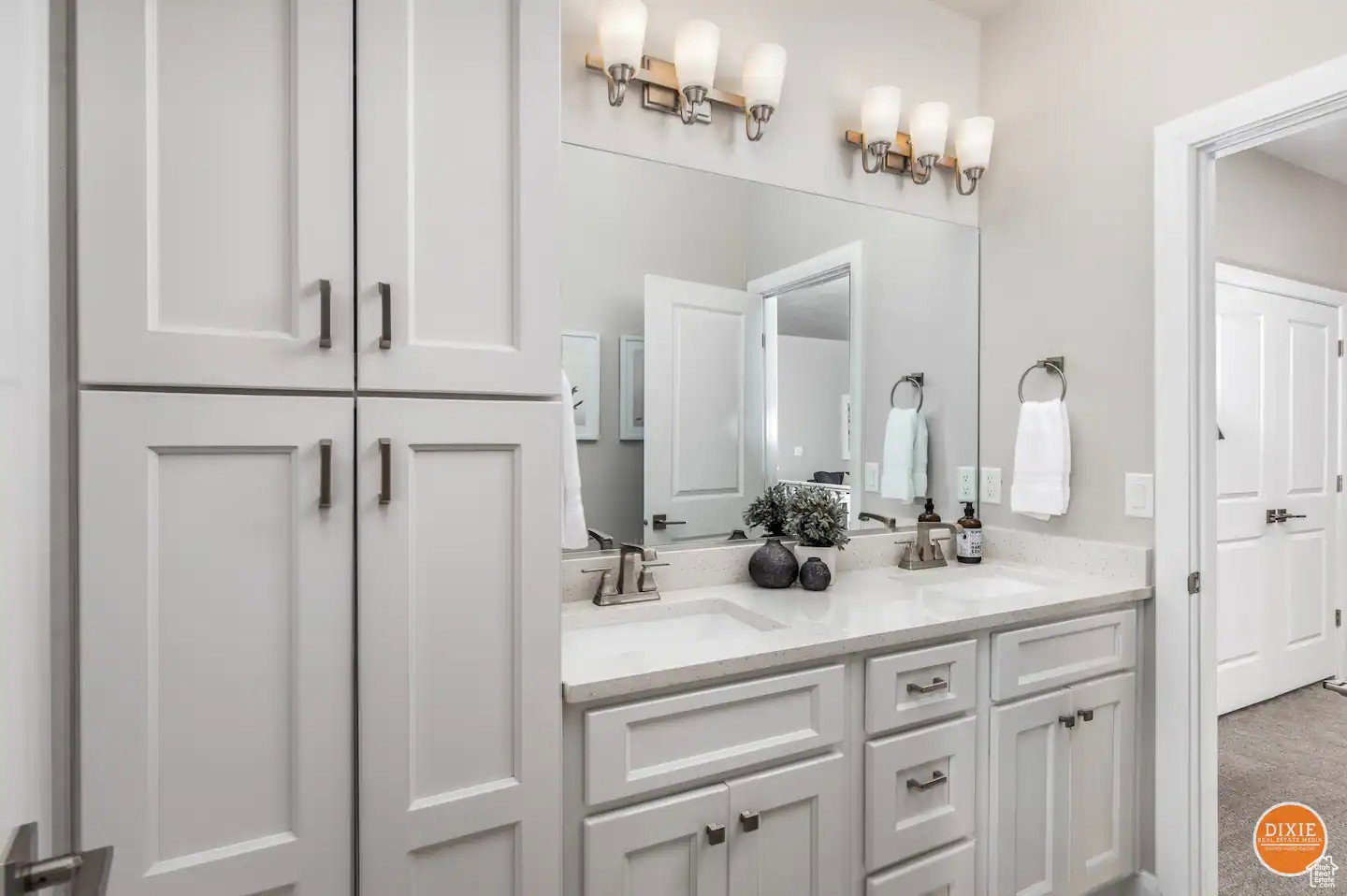 Dual sink vanity with white cabinetry, light-toned countertops, and brushed nickel hardware