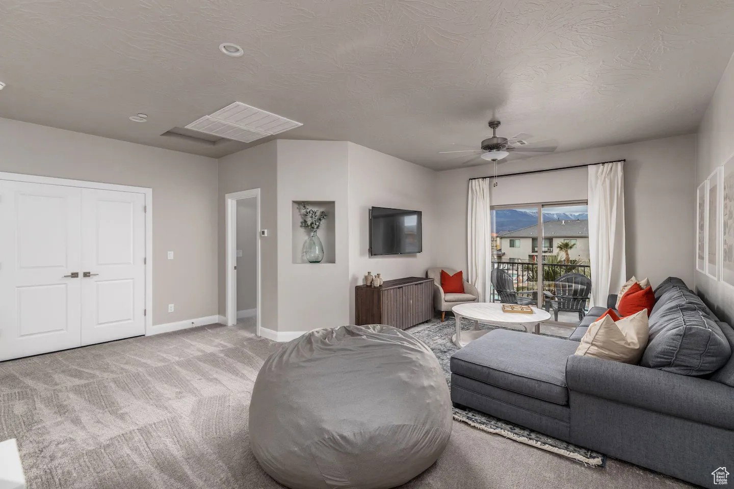 Spacious living area featuring neutral-toned carpeting, recessed lighting, and a ceiling fan
