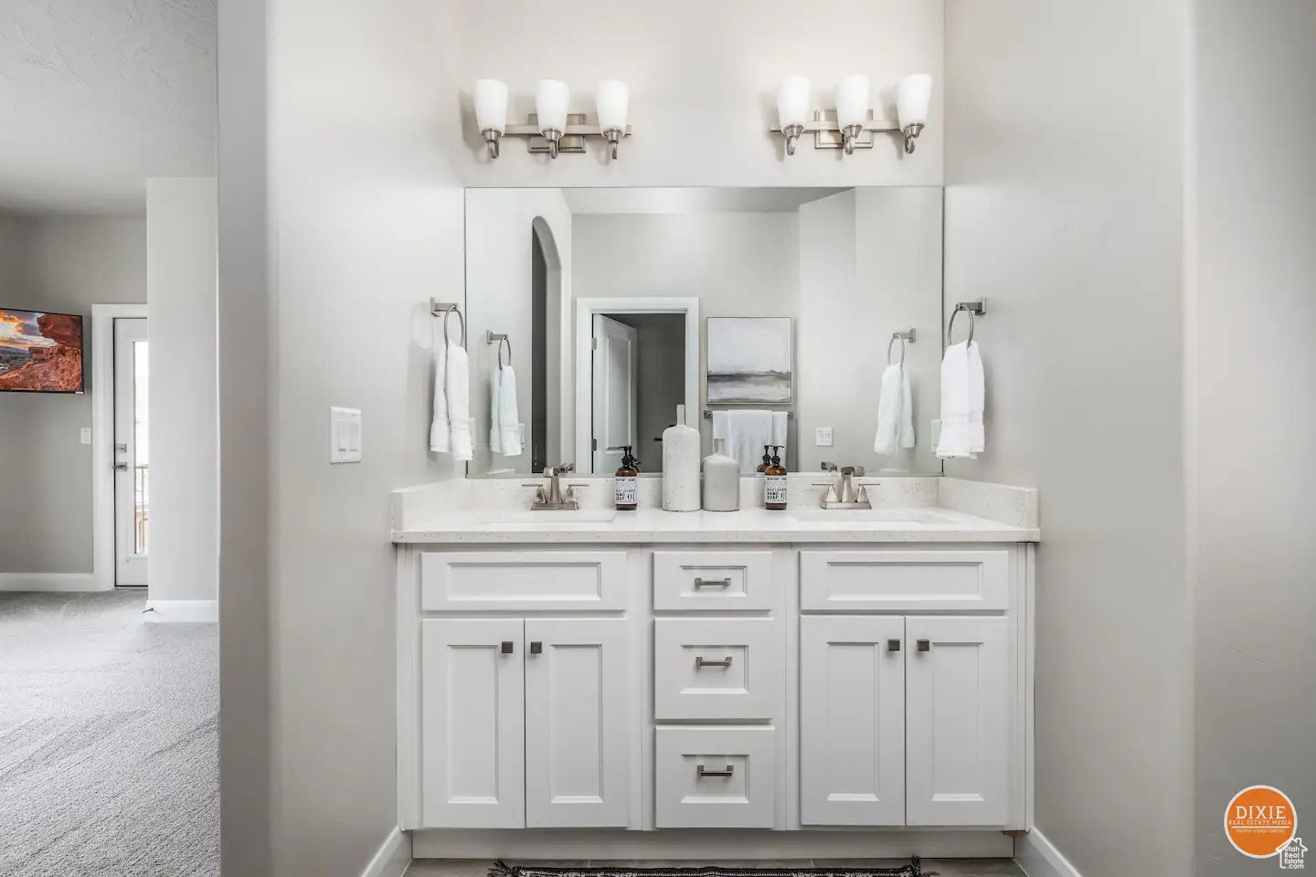 Dual vanity with white shaker-style cabinetry, a light-toned countertop, and dual wall-mounted light fixtures