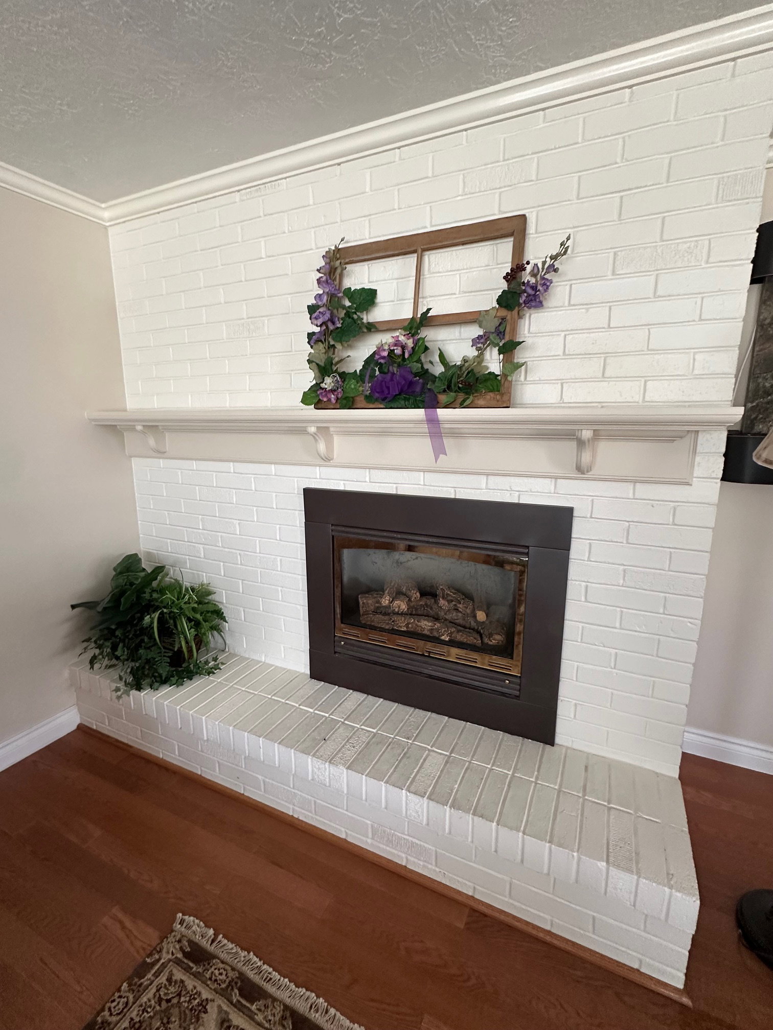 White-painted brick fireplace with gas insert, a mantel shelf, and a raised hearth.