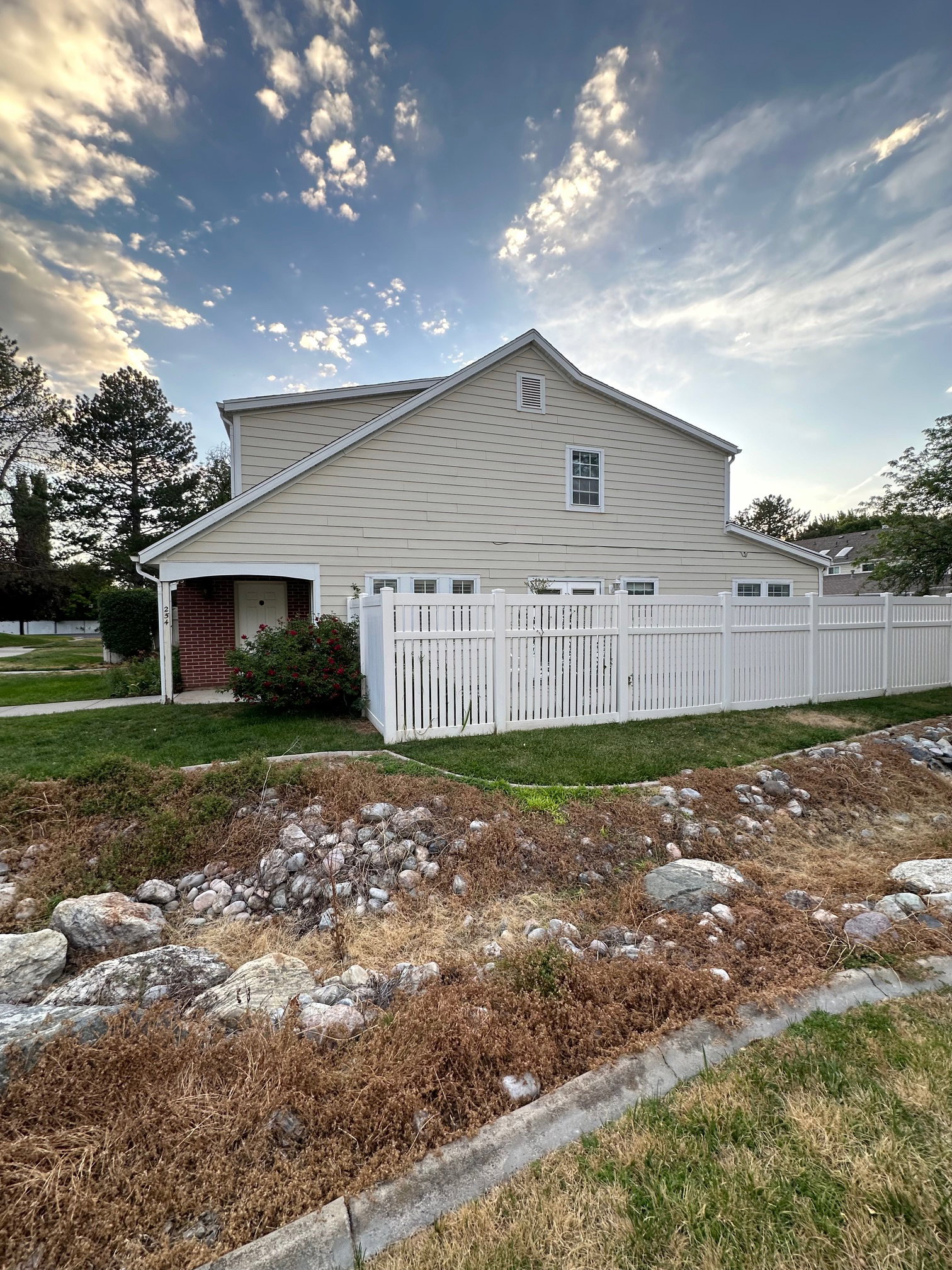 Two-story residence featuring light-colored siding and a white vinyl fence