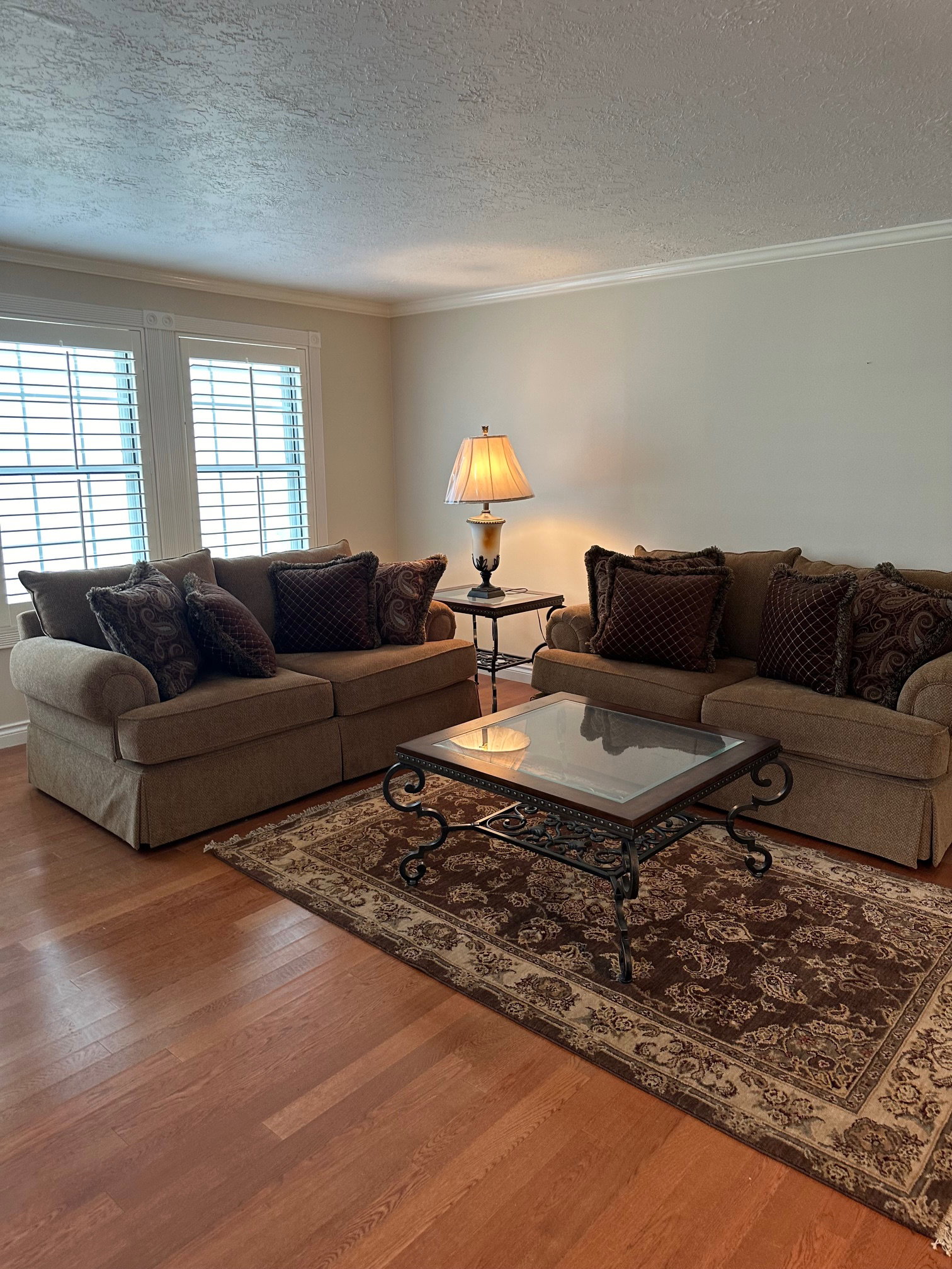 Expansive living area featuring warm wood-finish flooring, white crown molding, and neutral wall tones