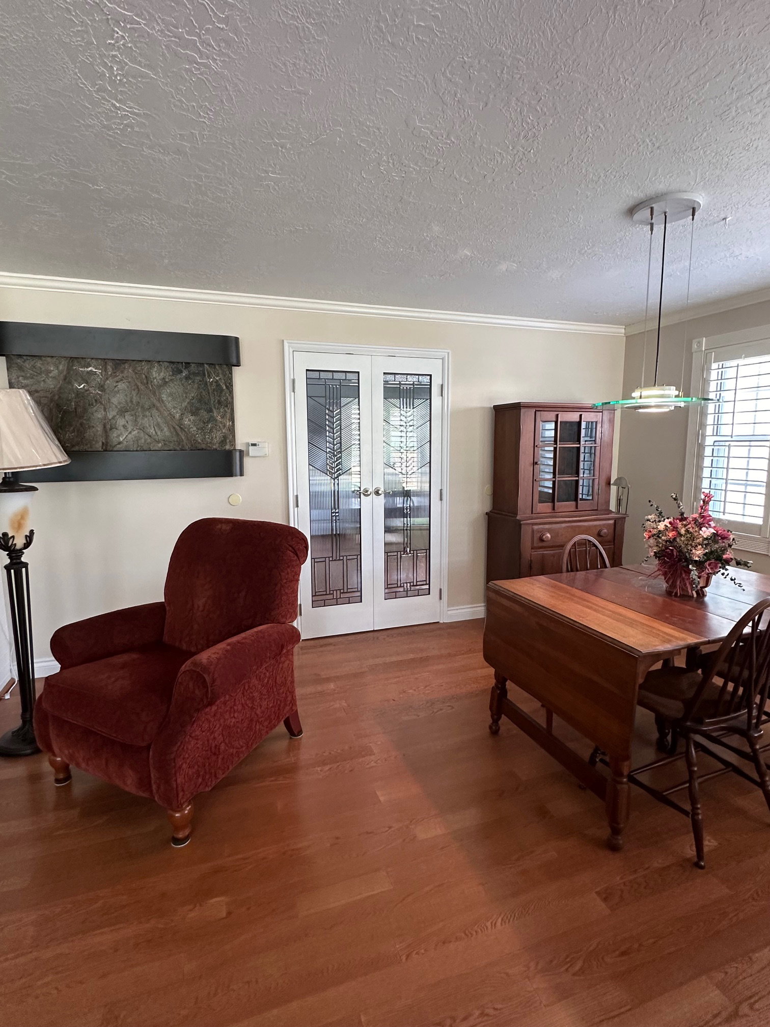 French doors with leaded glass panels, wood flooring, crown molding, wall-mounted water feature, and plantation shutters