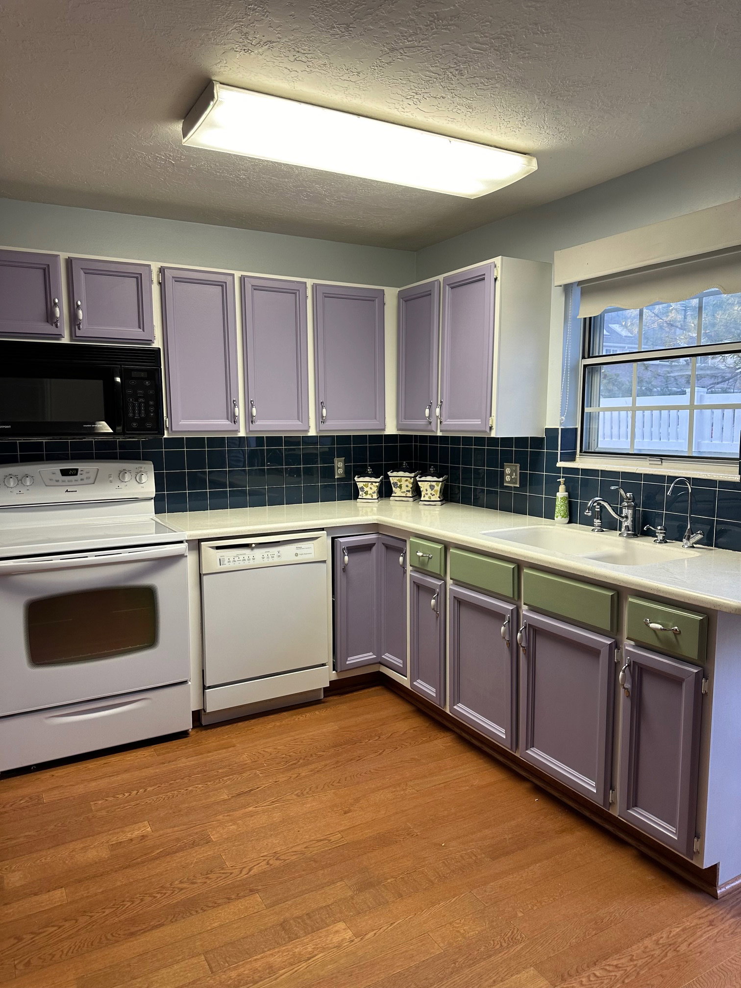 Kitchen featuring wood flooring, a double basin sink, and a black built-in microwave