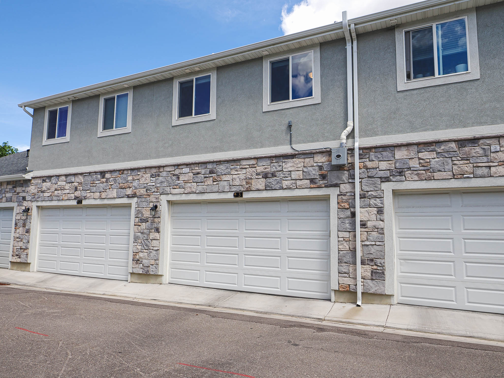Multi-unit exterior showcasing a stone facade and stucco upper level