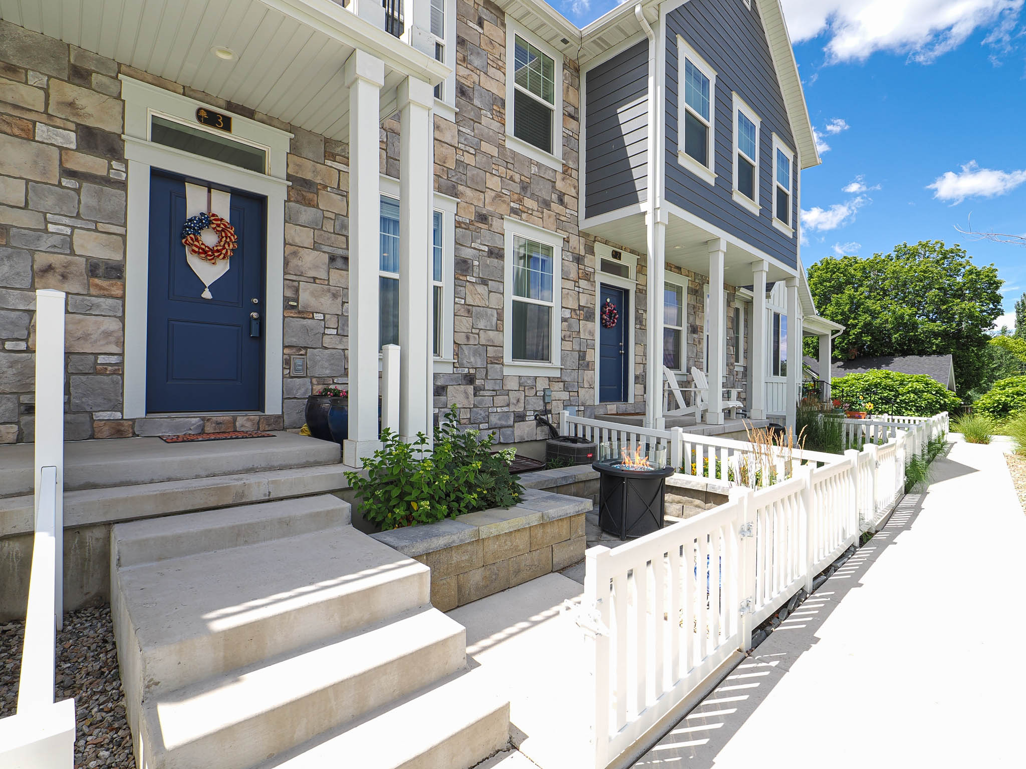 Stone and siding exterior with a navy blue entry door, white trim, and concrete steps