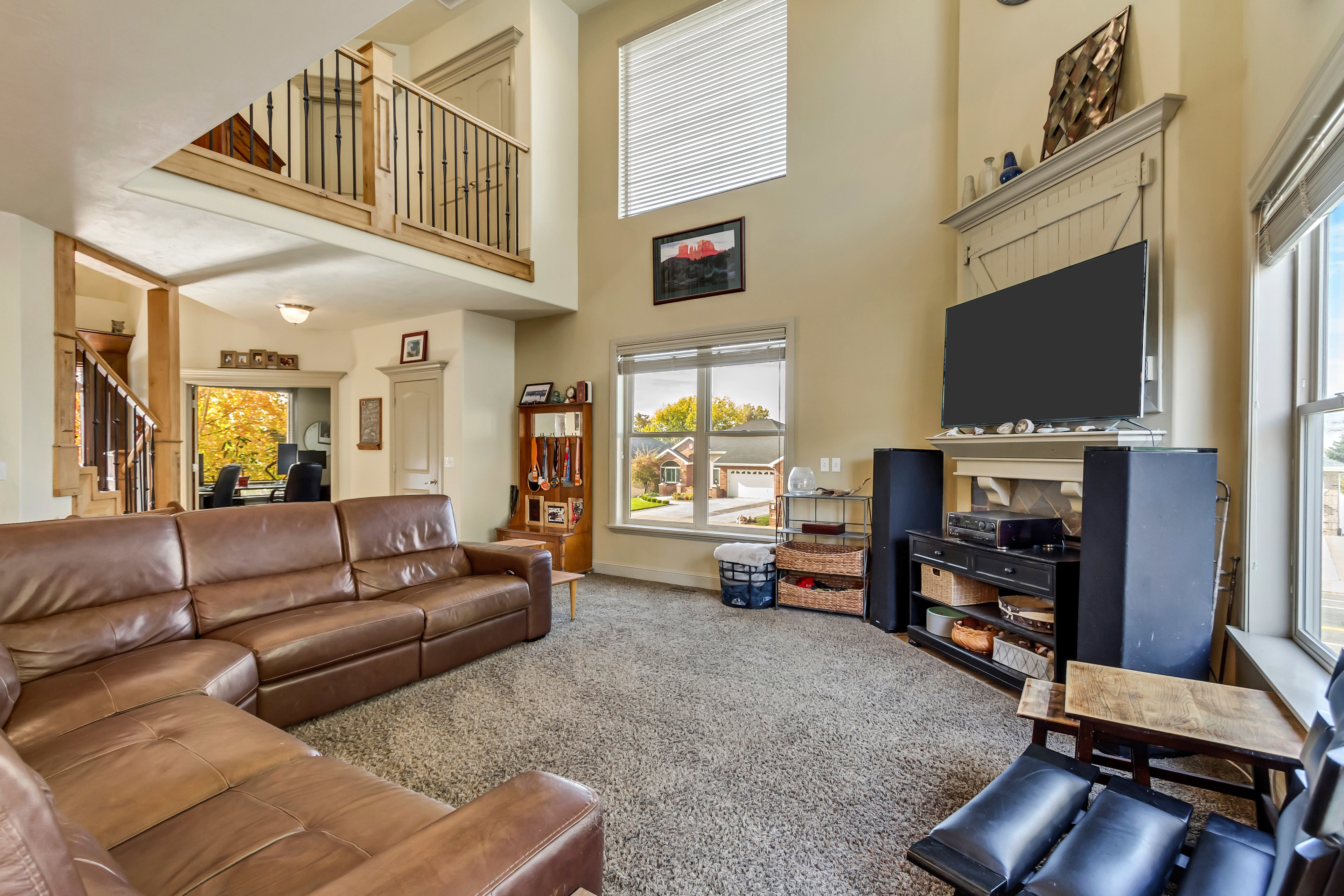 Open-concept living area with vaulted ceilings, carpet flooring, and abundant natural light from multiple windows