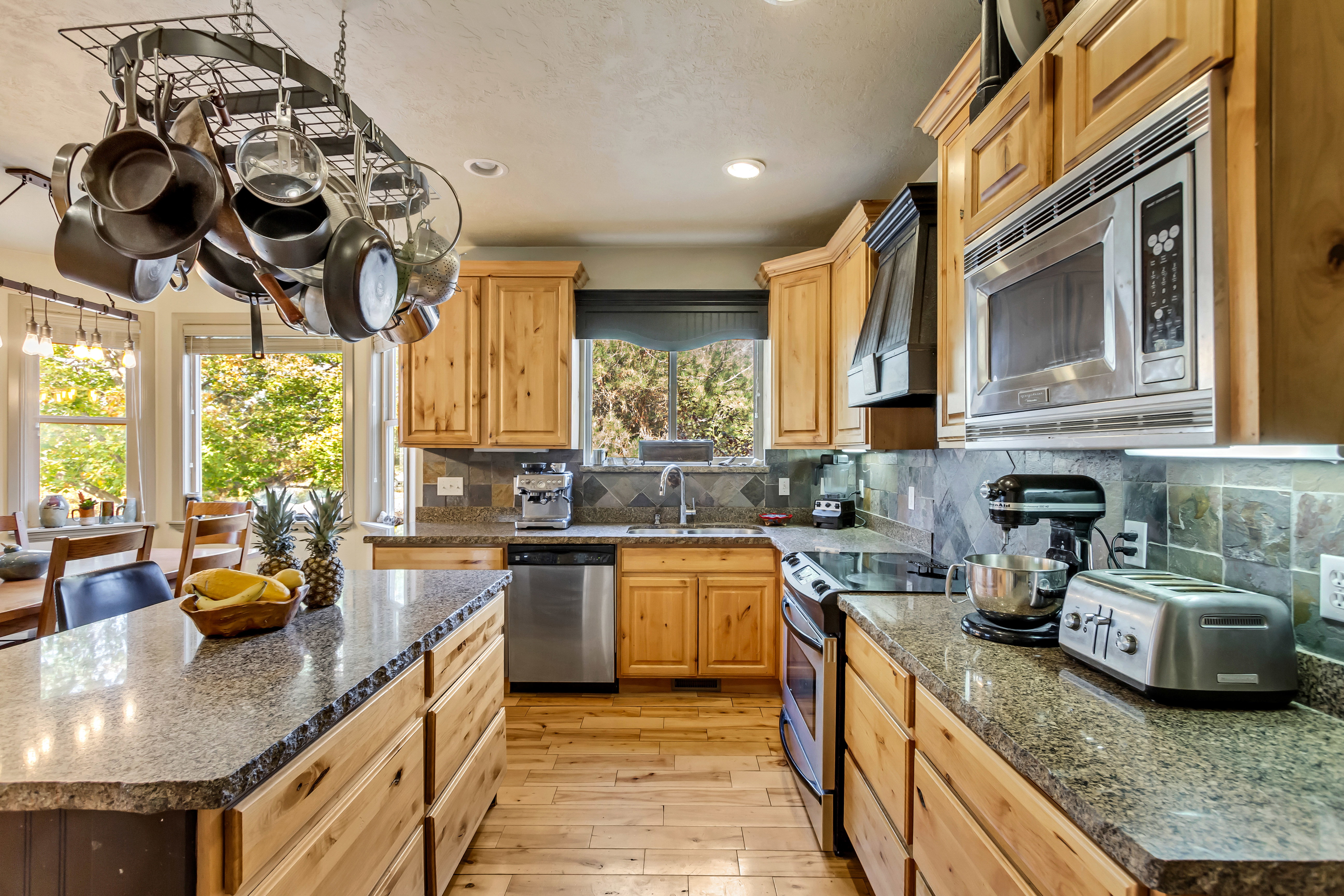 Kitchen featuring natural wood cabinetry, light-toned wood-finish flooring, and granite countertops