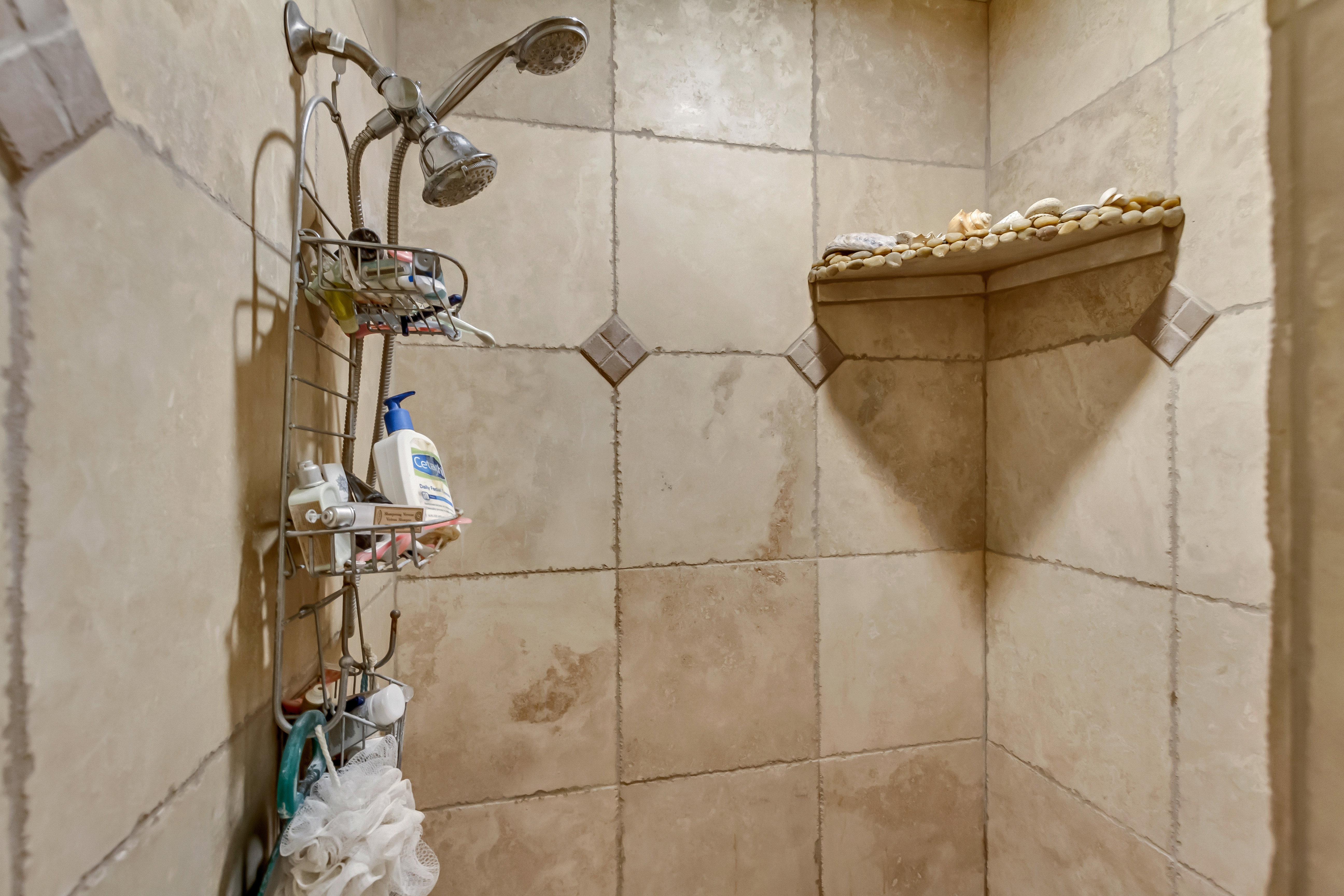 Shower enclosure featuring natural-toned square tiles with contrasting grout and decorative diamond accent tiles