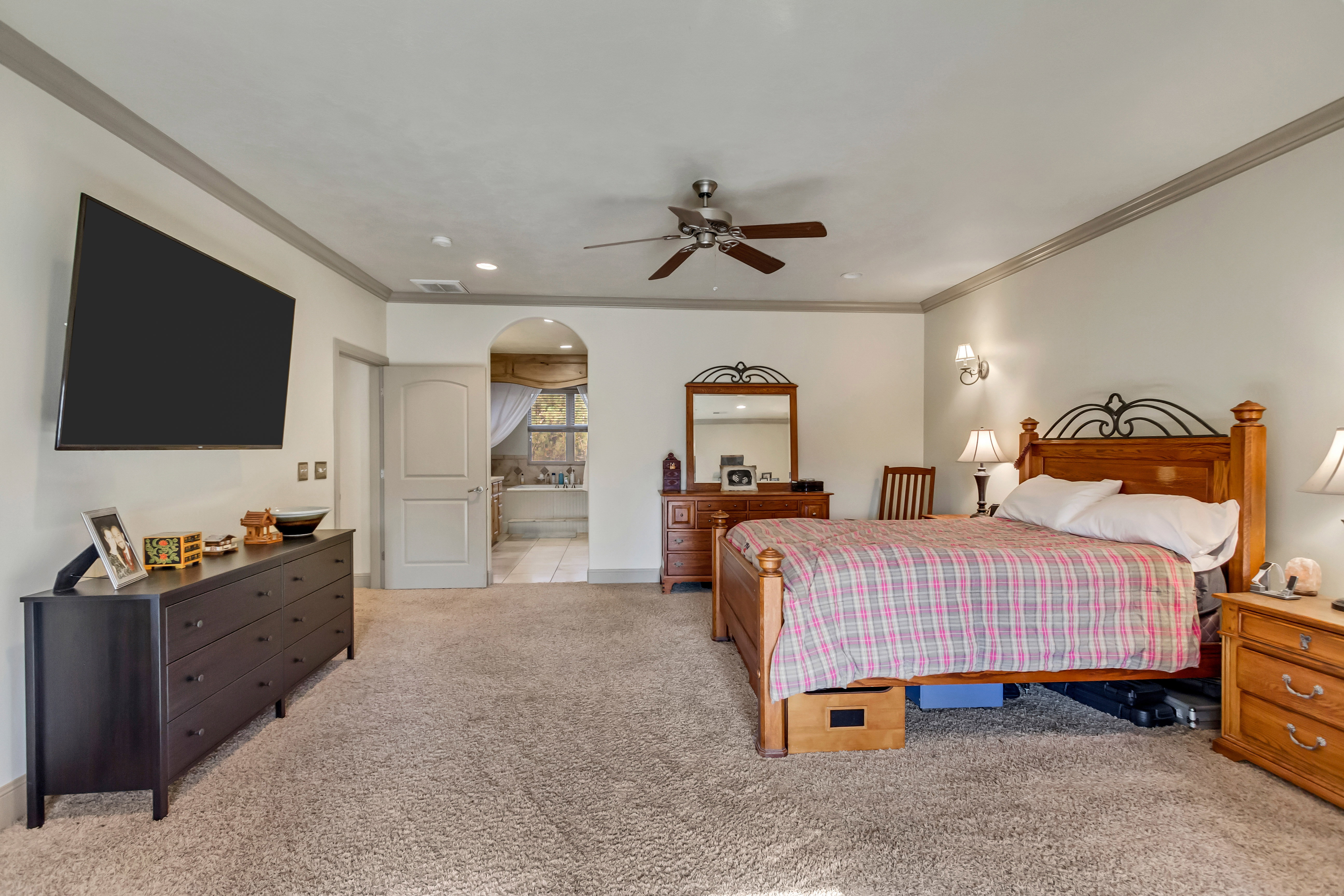 Spacious carpeted room featuring a ceiling fan, crown molding, and recessed lighting