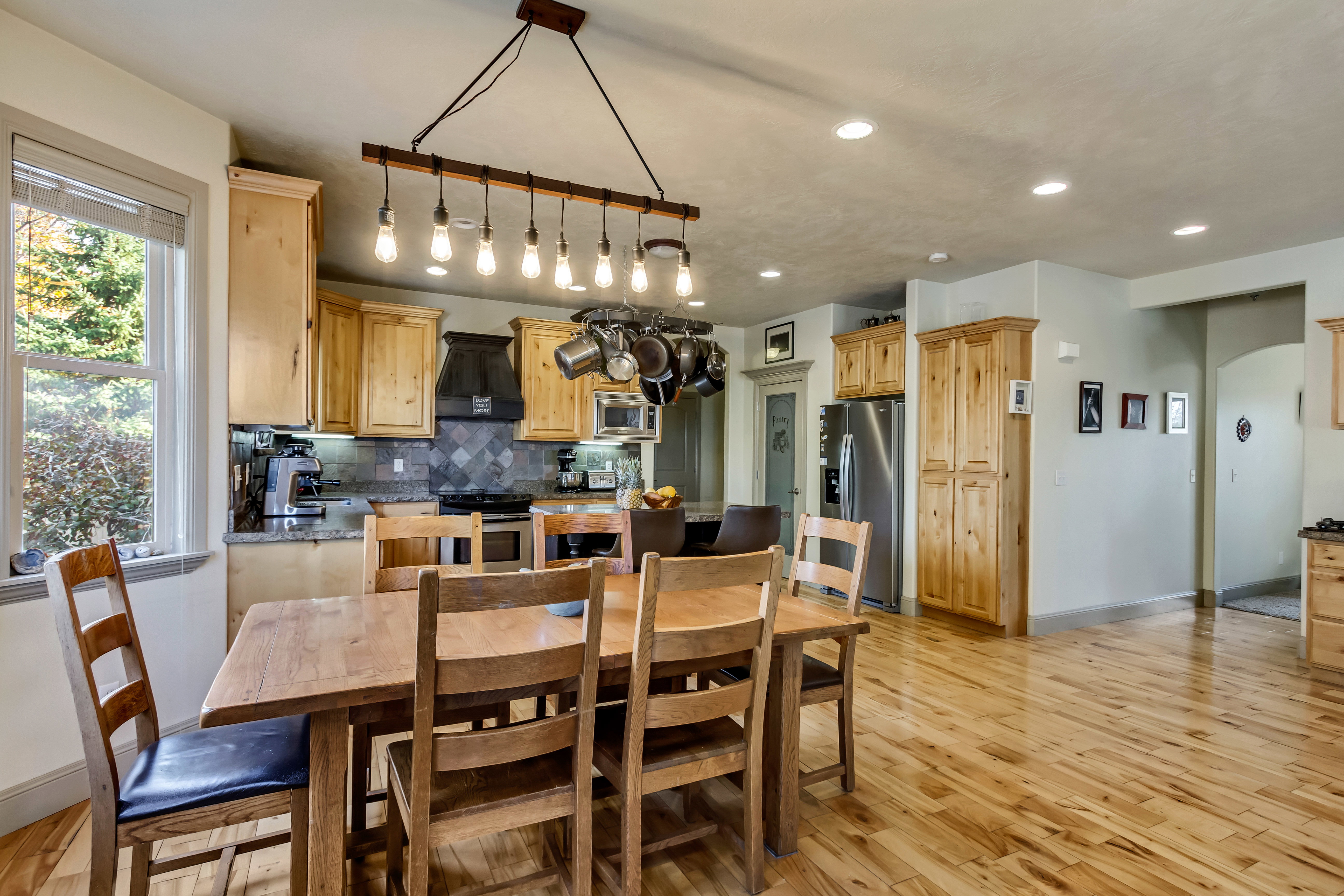 Kitchen and dining area featuring wood-finish flooring, recessed lighting, and a window with blinds
