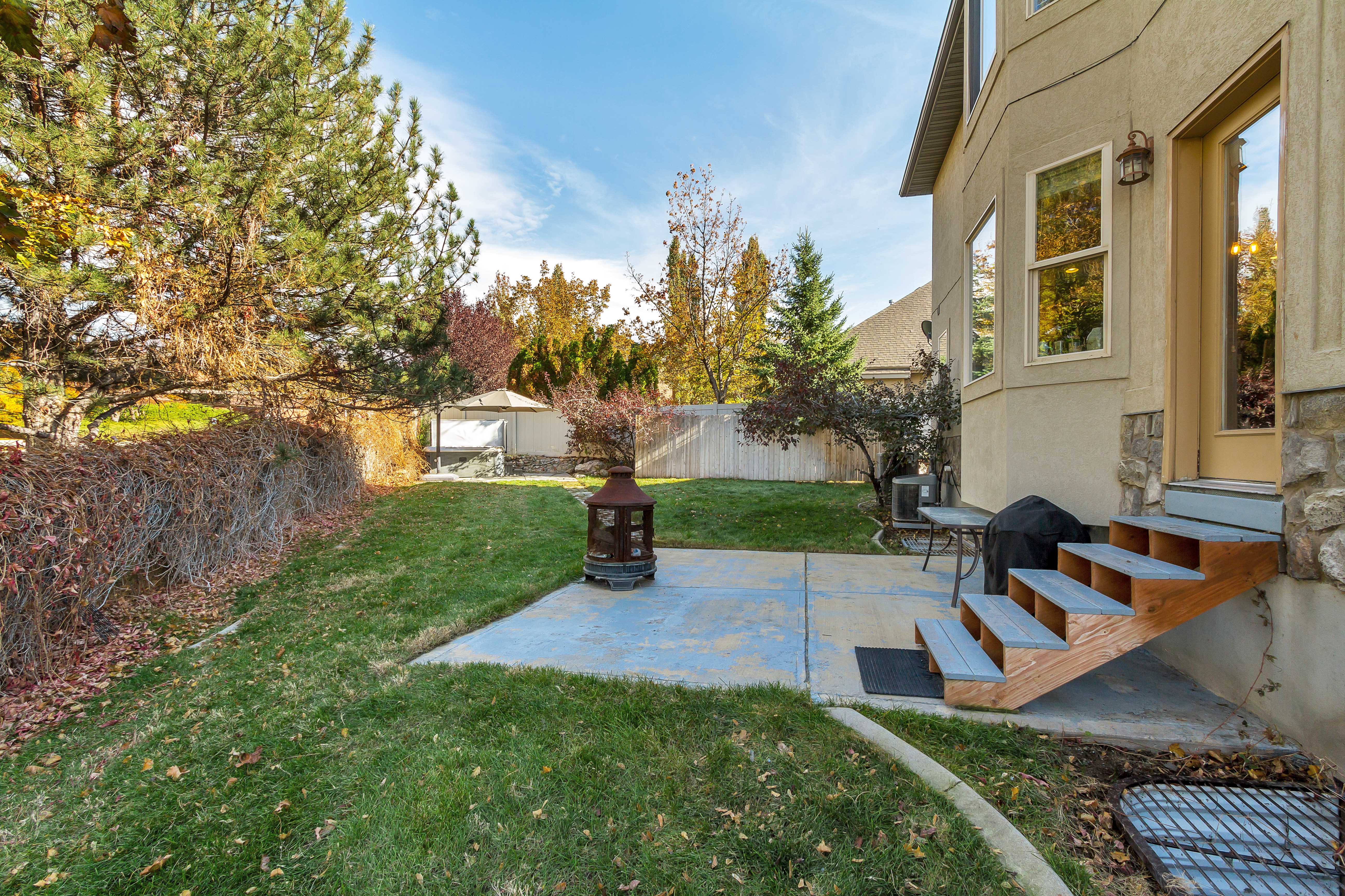 Spacious backyard featuring a concrete patio, exterior access stairs with wood treads, and a stucco and stone exterior