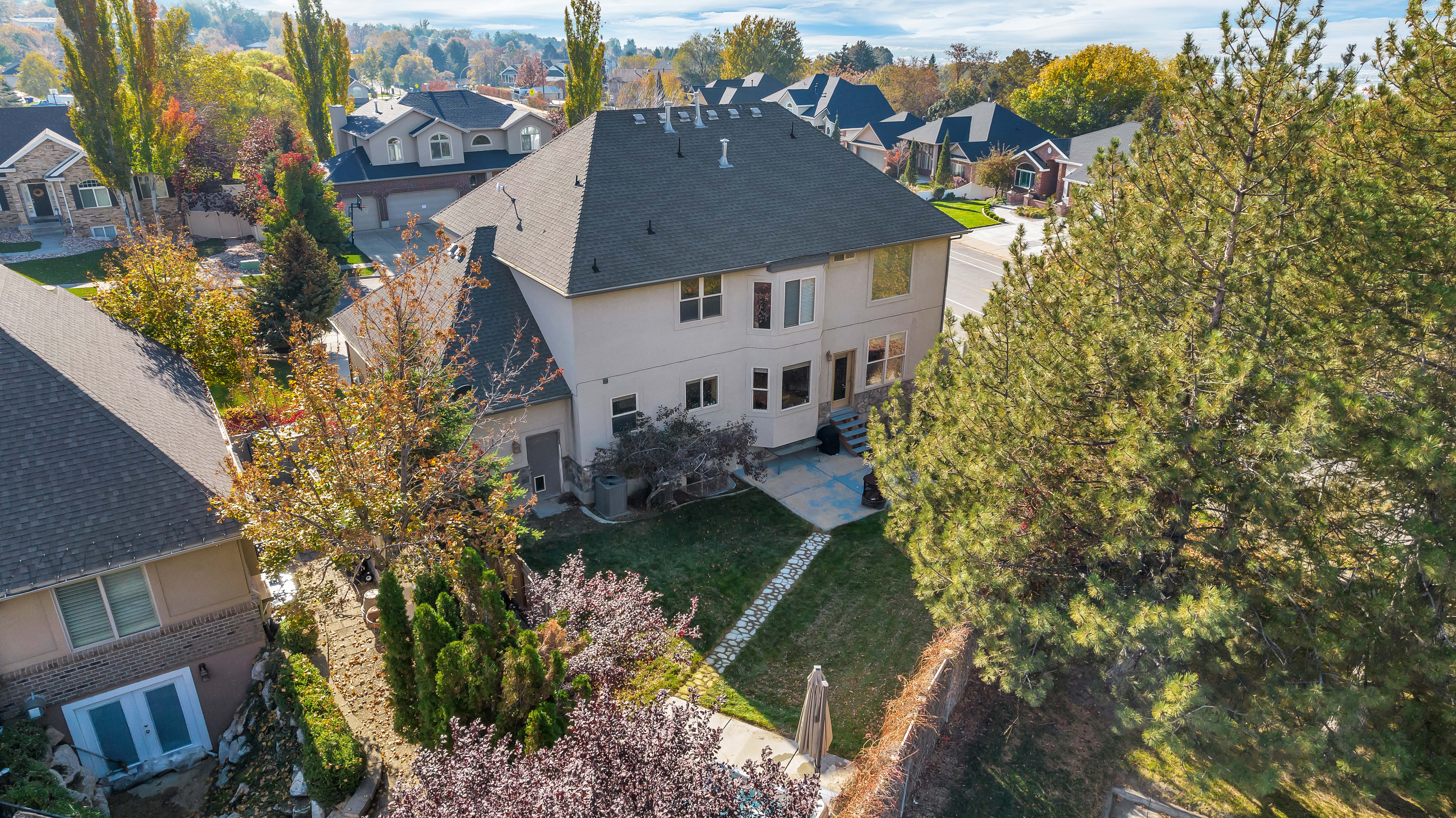 Rear exterior featuring a multi-story design with a light-toned facade and dark shingle roof