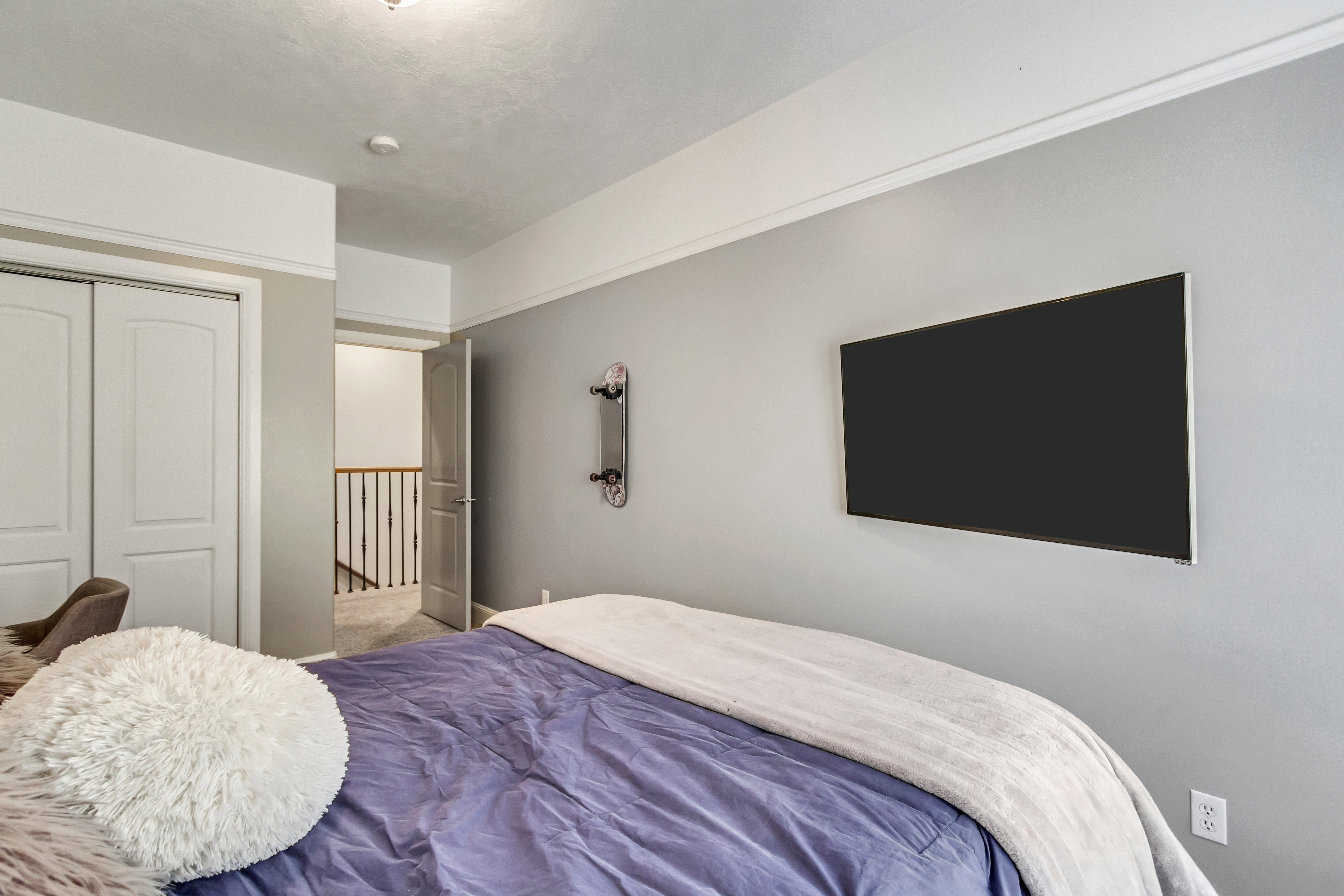 Bedroom featuring light gray walls, white crown molding, and a mounted flat-panel display