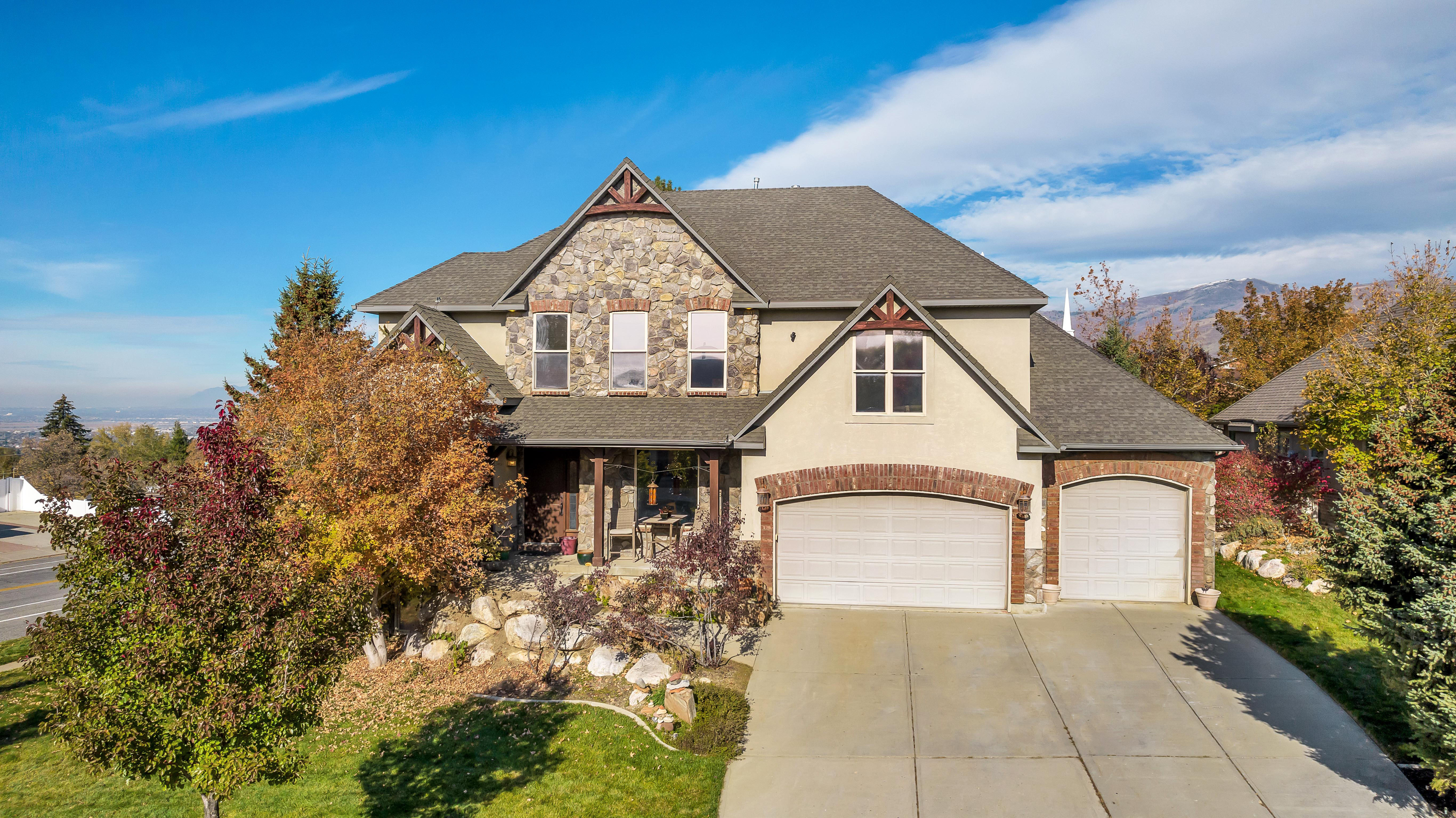 Stately residence featuring a stone and stucco exterior, arched brick accents, a gabled roofline, and an attached two-car garage